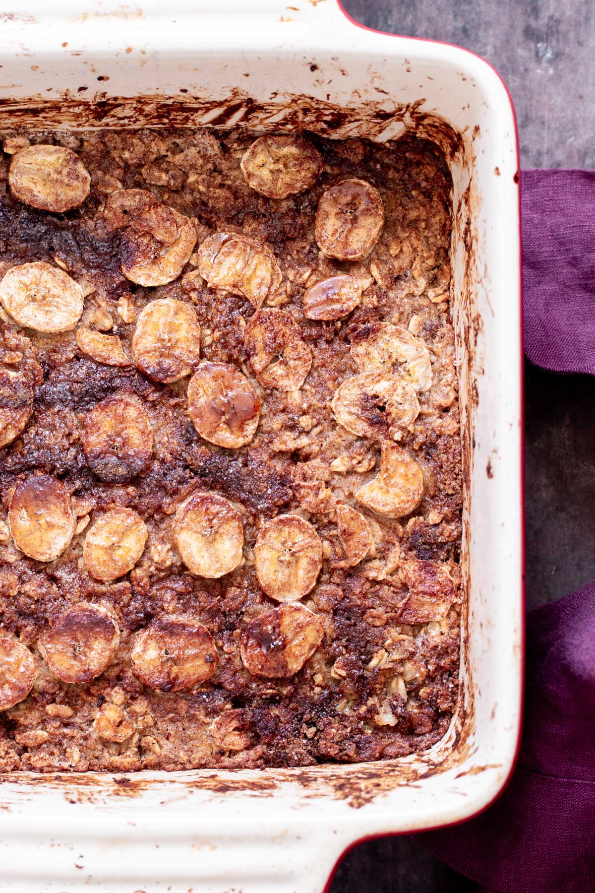 a casserole dish with banana oatmeal bars topped with sliced bananas