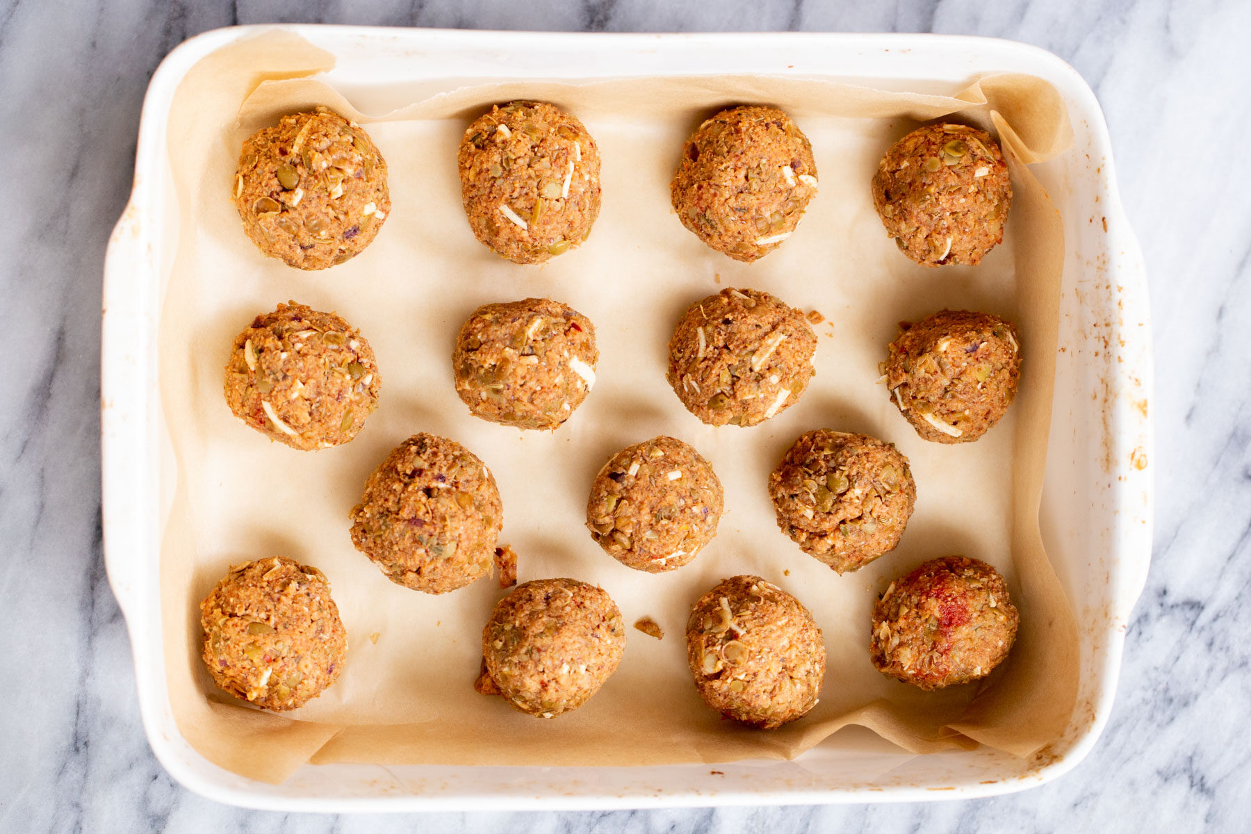 vegan lentil meatballs vegan lentil meatballs with cheese shreds in a white casserole dish