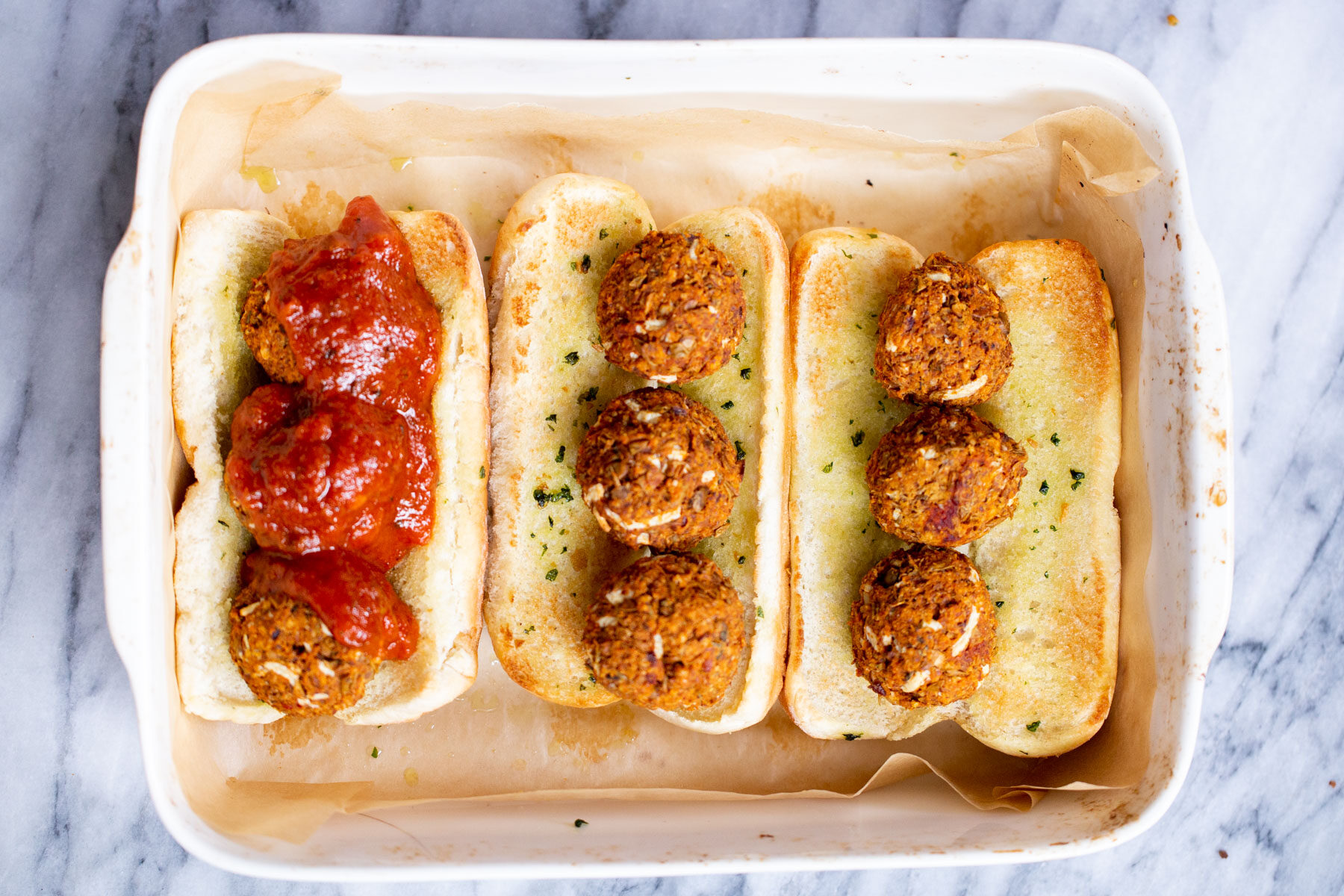 vegan meatball subs  a casserole dish with vegan meatball subs topped with lentil meatballs and marinara sauce