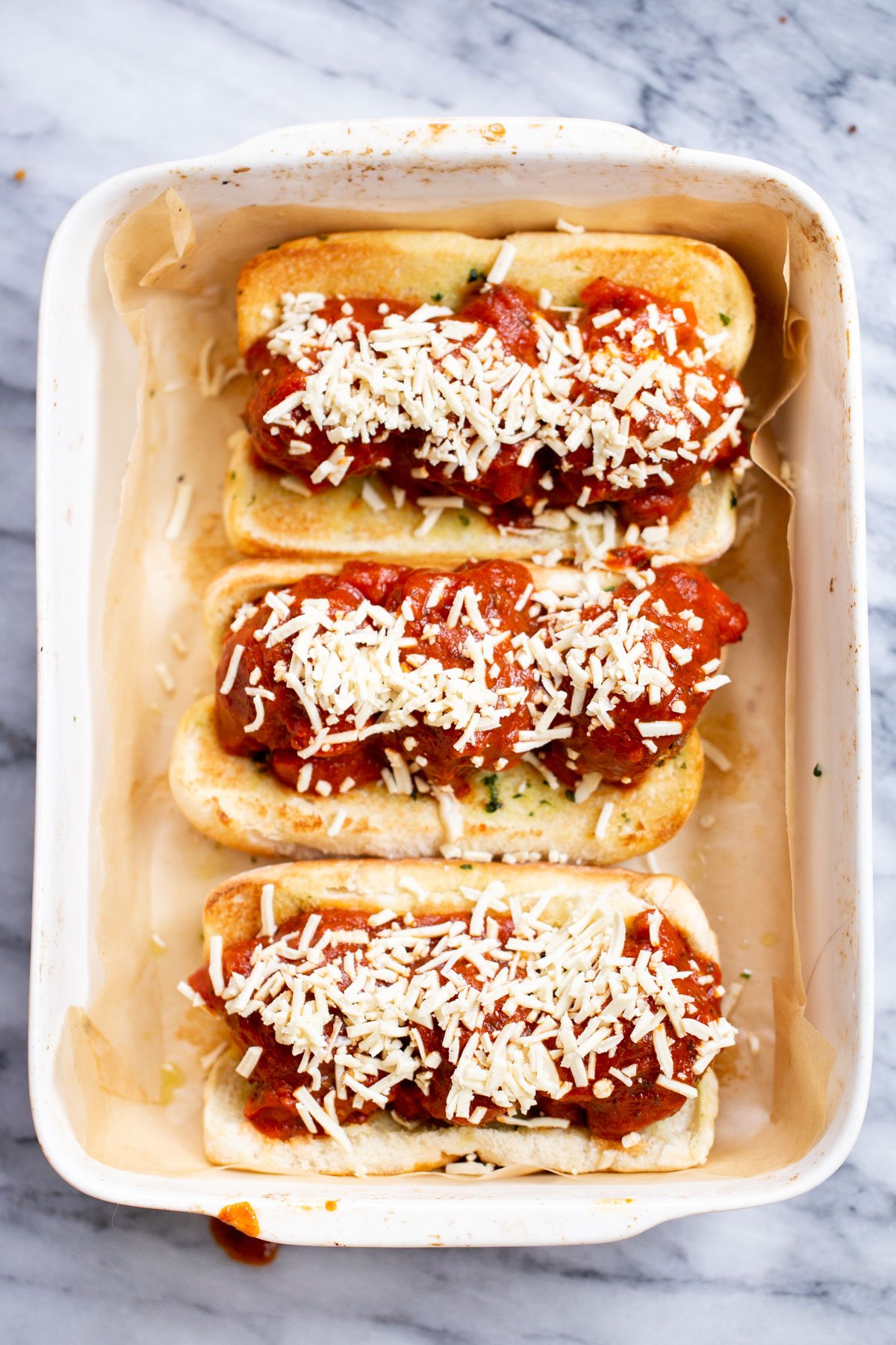 vegan meatball subs a casserole dish with vegan meatball subs topped with shredded cheese
