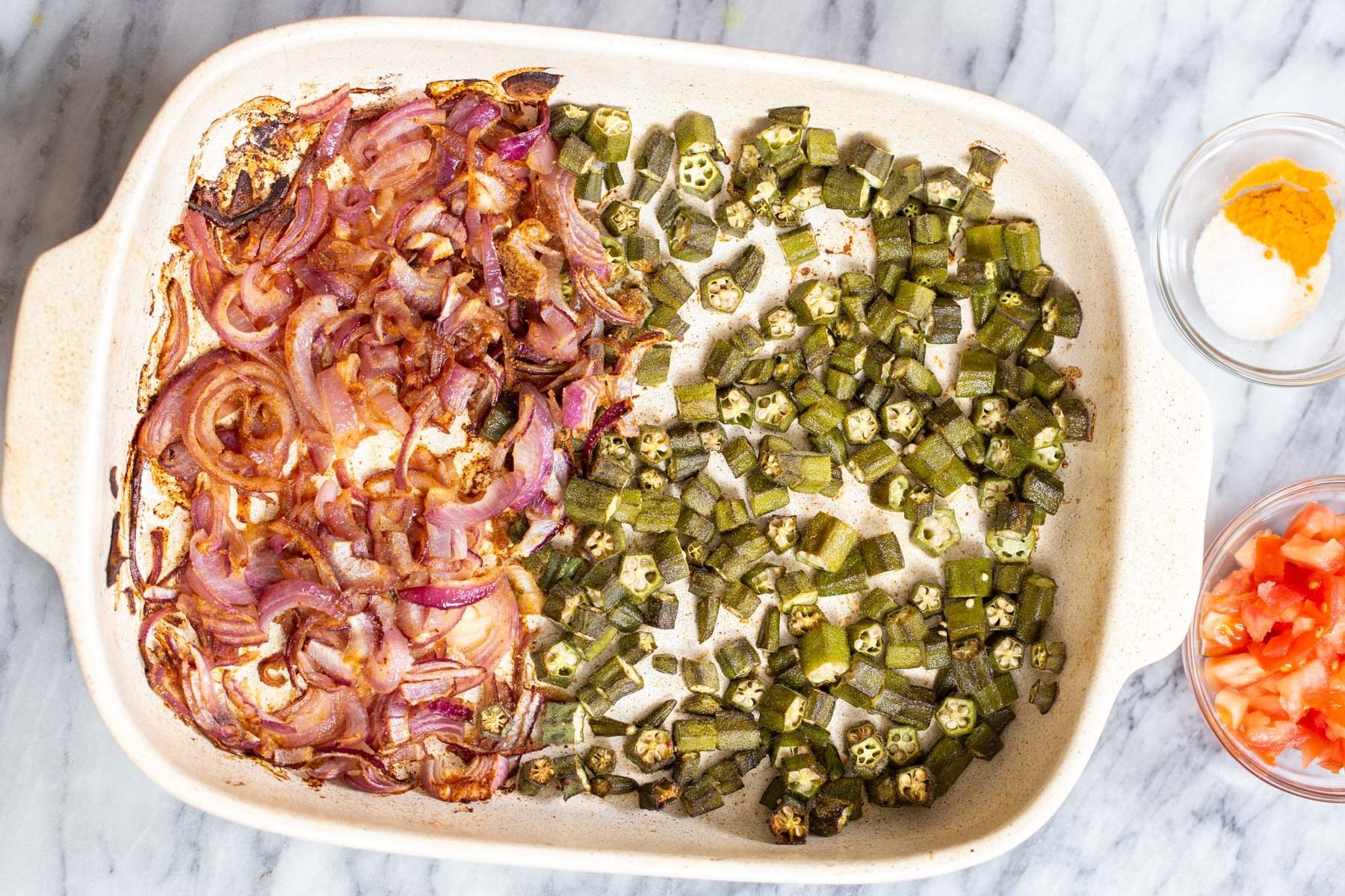 baked red onion and okra in a white casserole dish