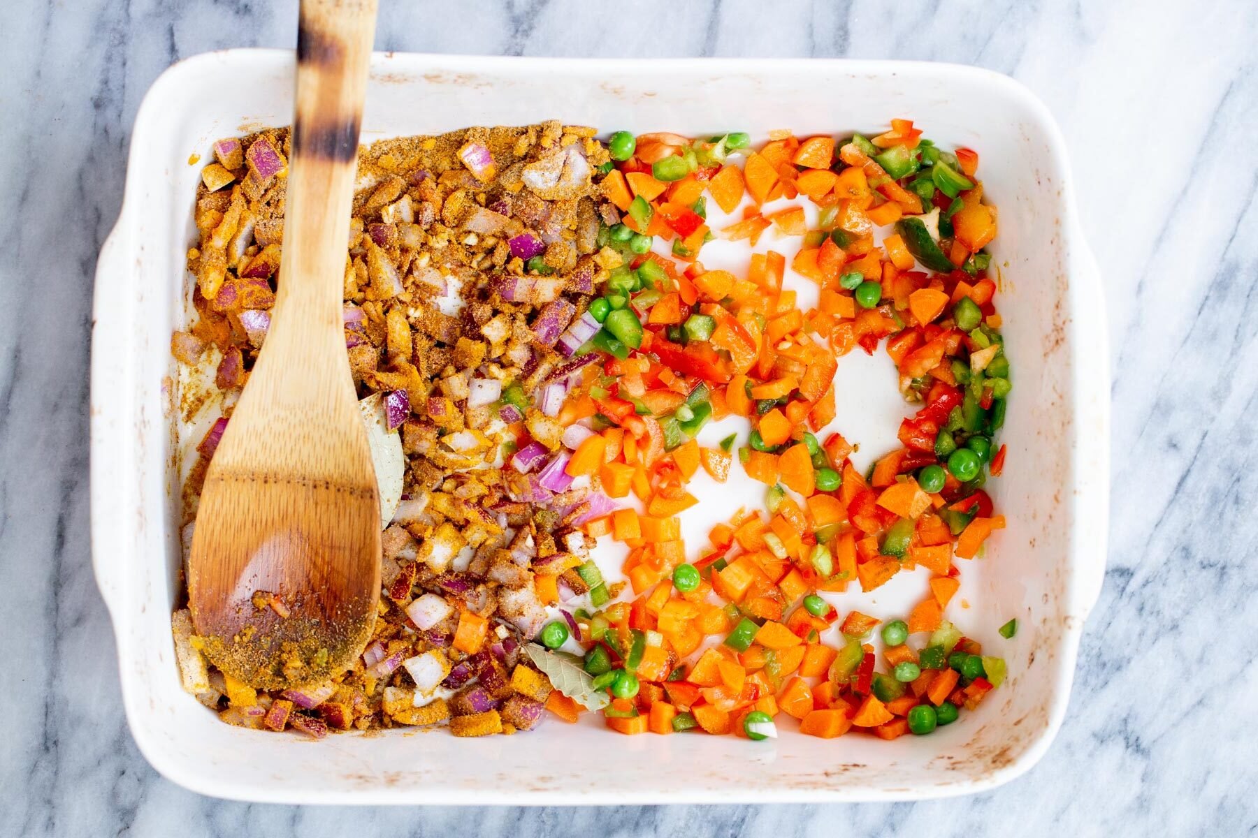 spiced being mixed into onion in a casserole dish