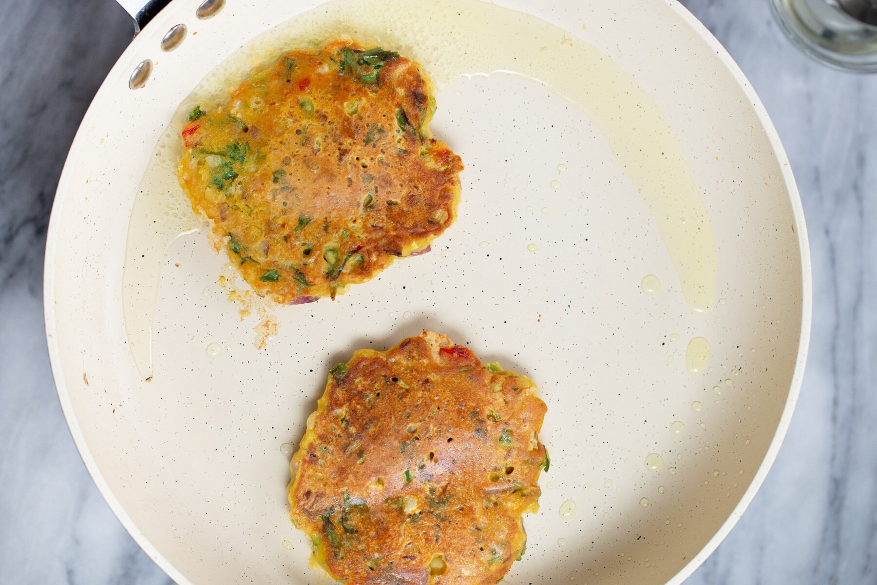 vegan chickpea flour pancakes frying in a skillet