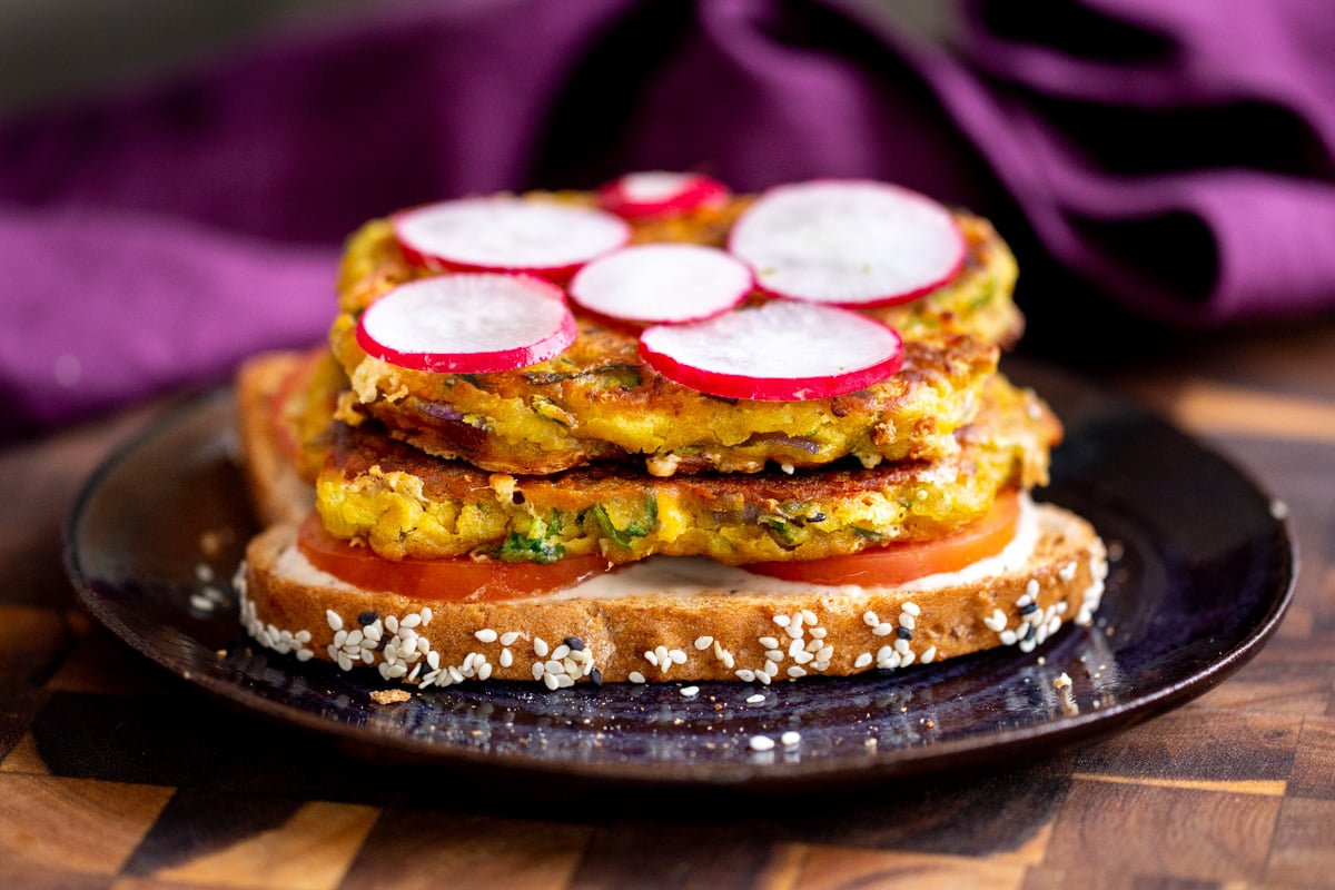vegan breakfast sandwich being assembled with chickpea flour pancakes and radishes
