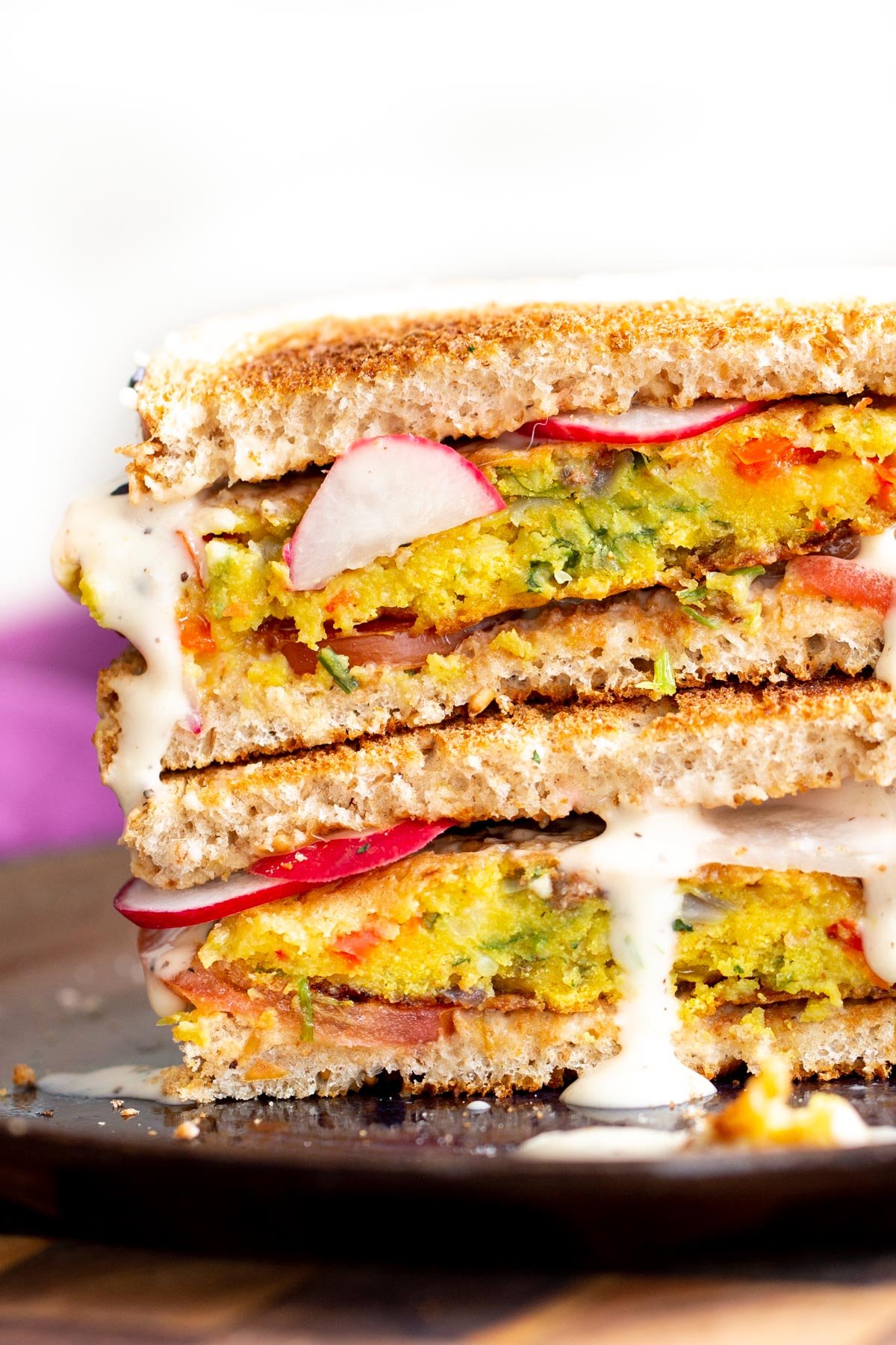 stacked vegan breakfast sandwich filled with chickpea flour pancakes and vegetables