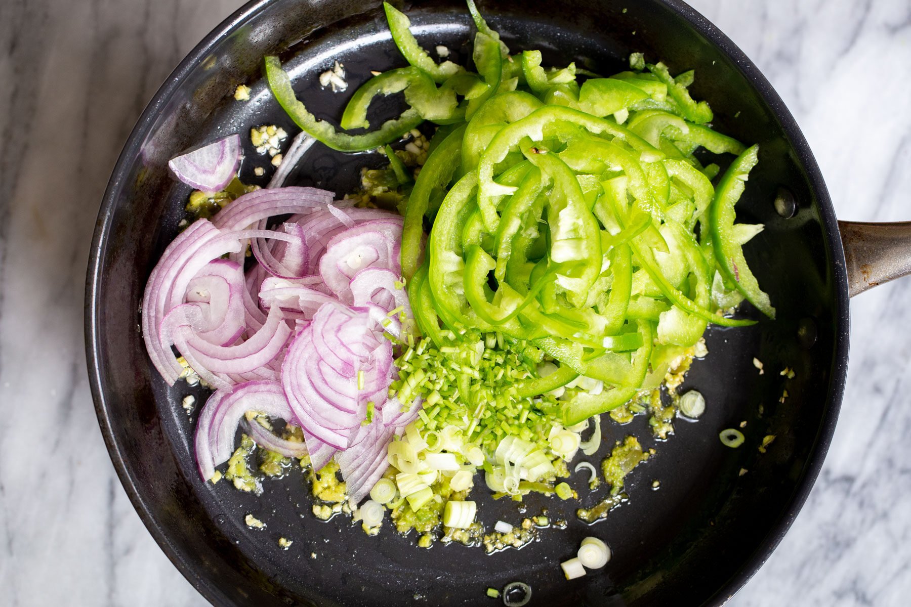 sliced onion and green bell peppers in a sauteeing pan