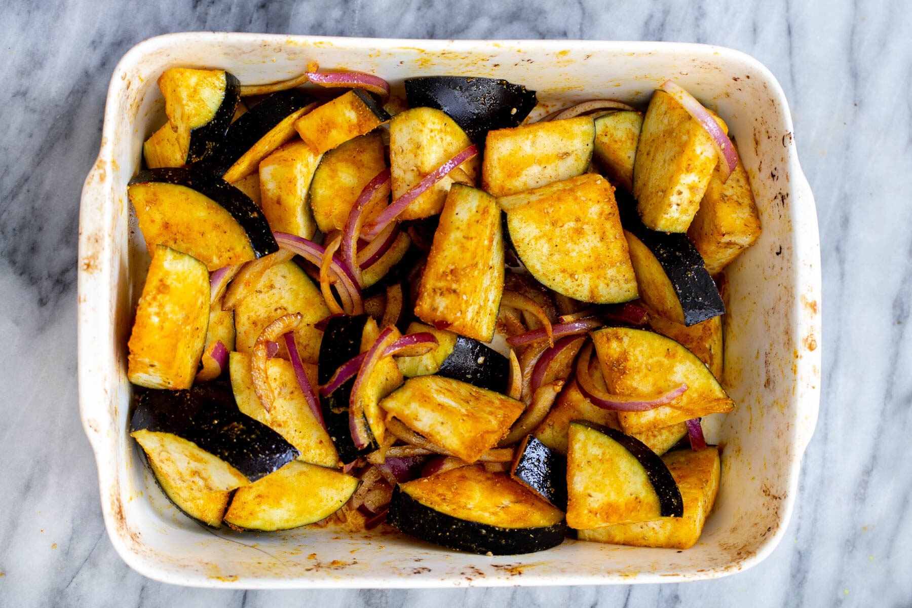 spiced eggplant spices and onions in a white casserole dish