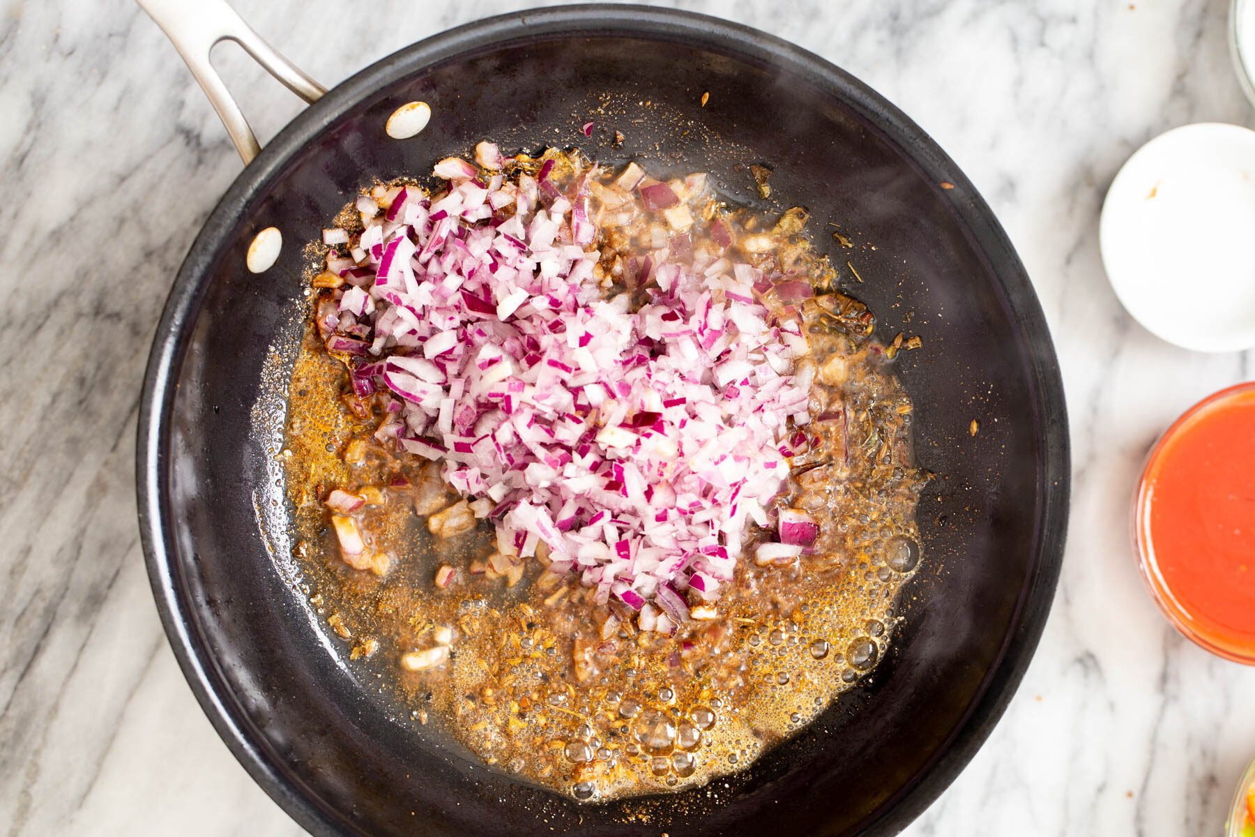 onions and spices in a black skillet