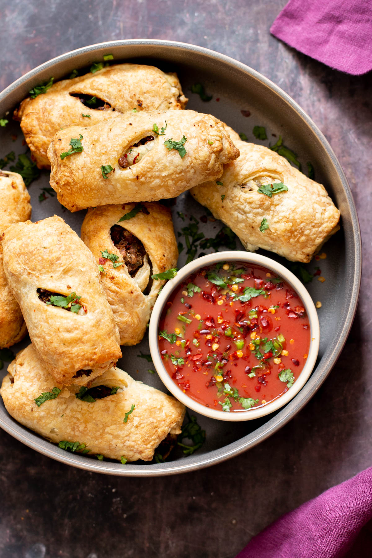 a plate of vegan sausage rolls with a small dish of tomato sauce