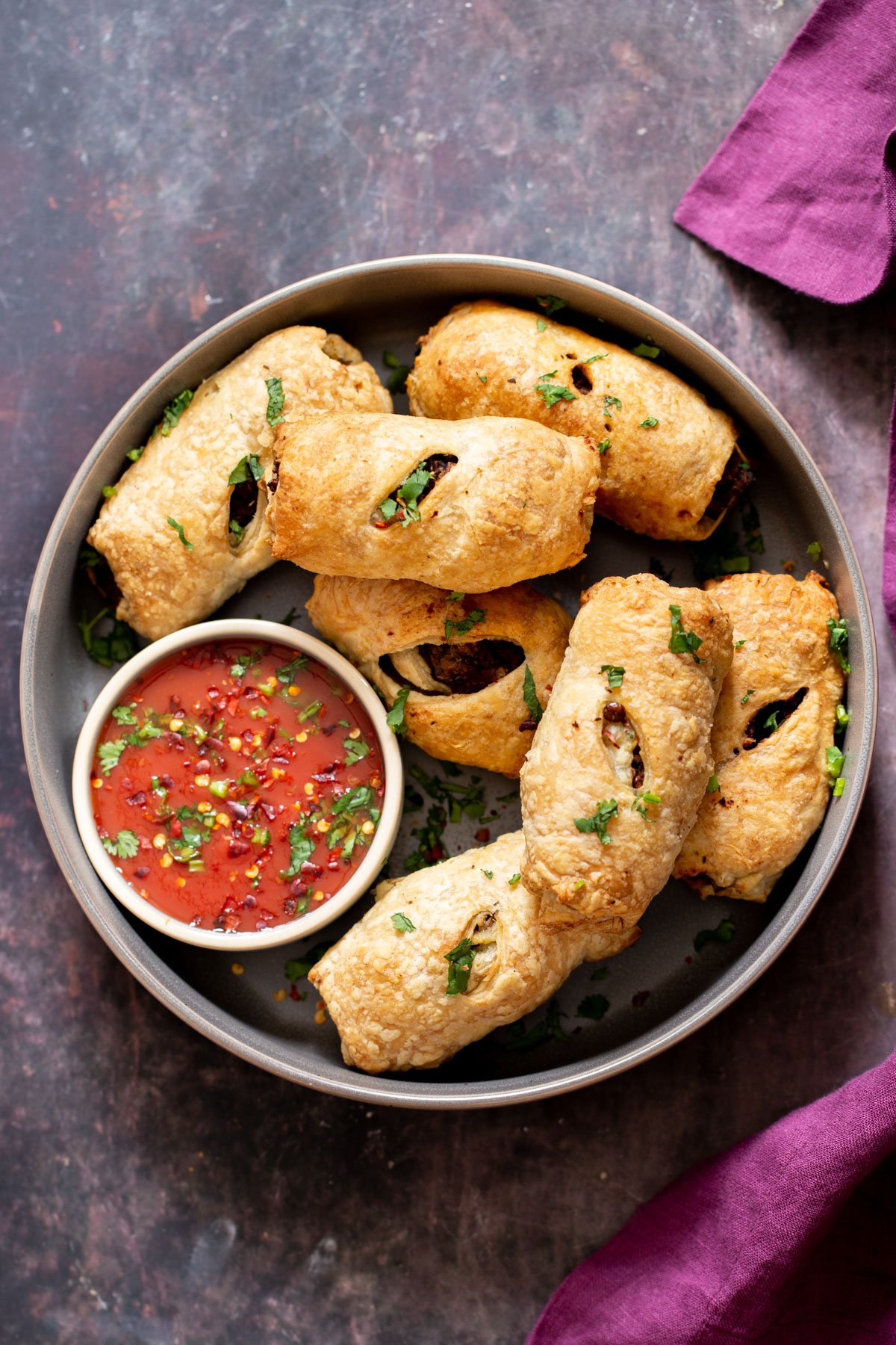 overhead shot of vegan sausage rolls next to a small dish with tomato sauce