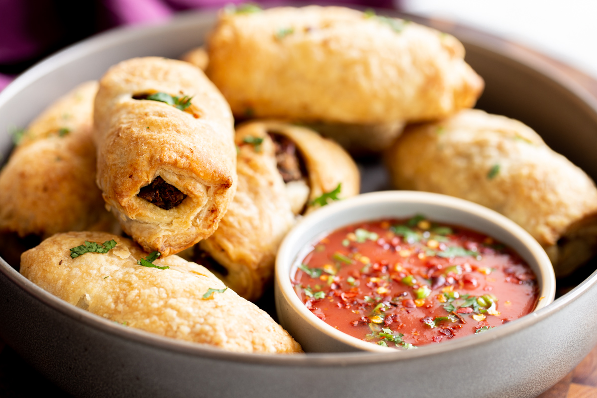 vegan sausage rolls next to a small dish of tomato sauce 