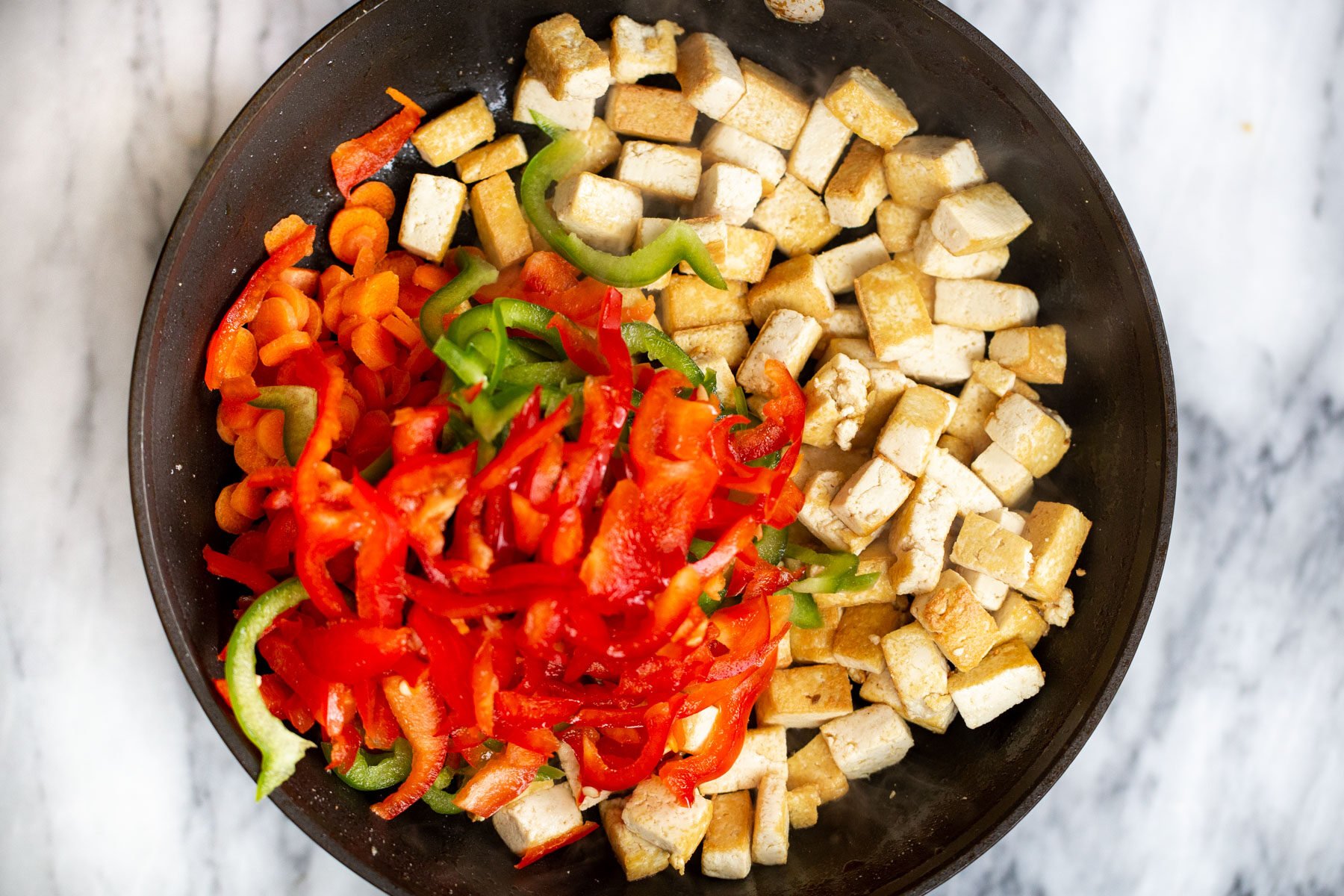 veggies and tofu cubes in a black skillet