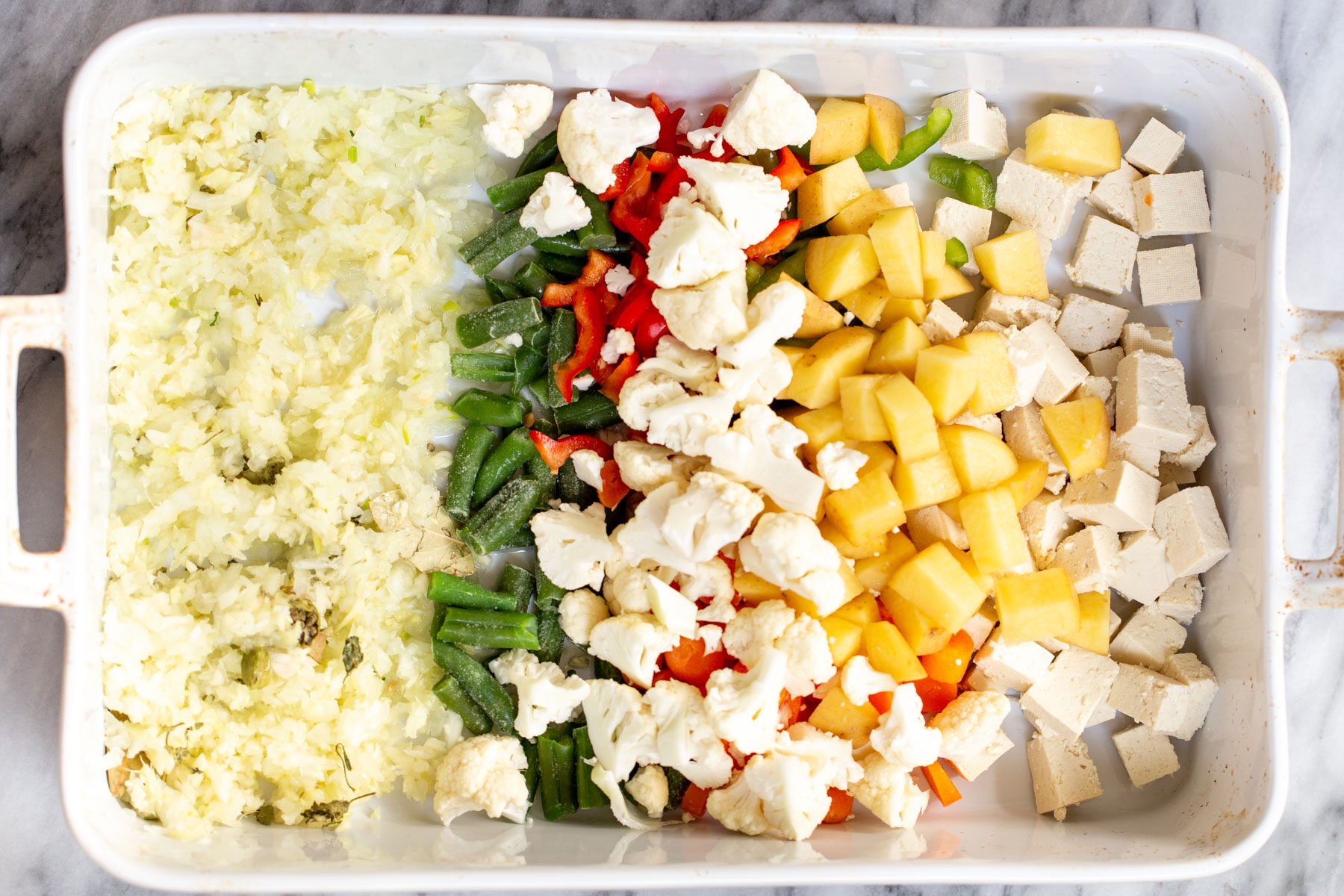 Navratan Korma  tofu cubes, veggies and minced ginger and garlic in a white casserole dish