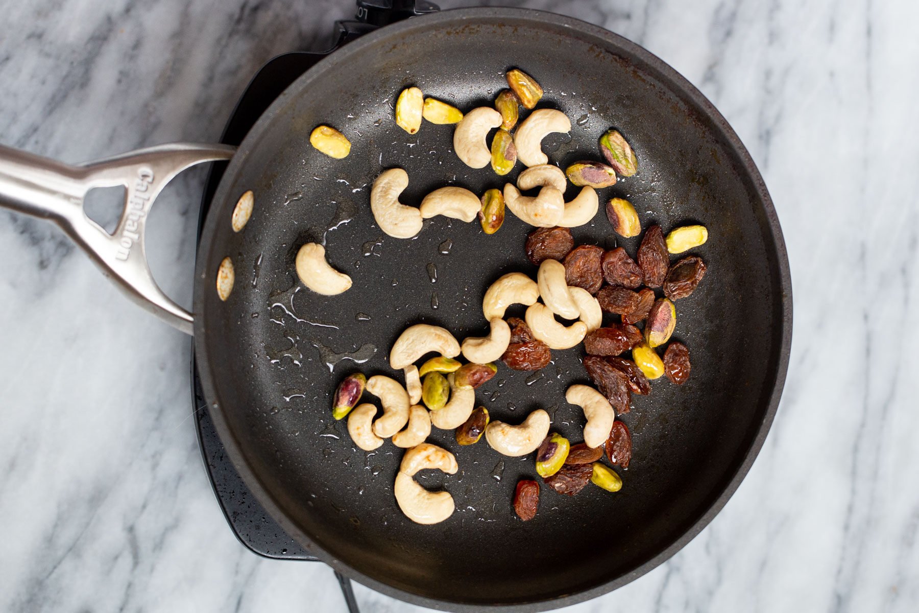 Navratan Korma  a black skillet with toasted nuts