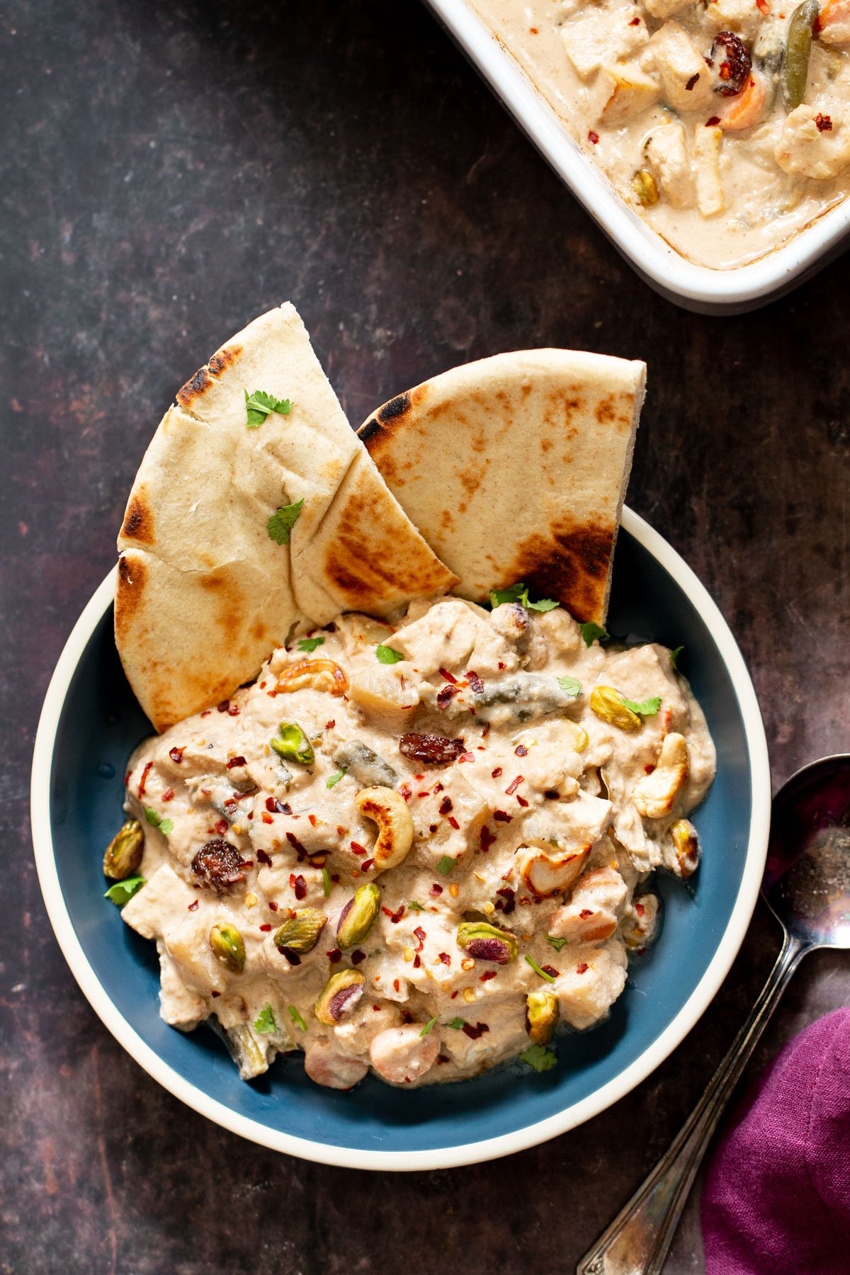 Navratan Korma served in a bowl with some pita bread and sprinkled with nuts