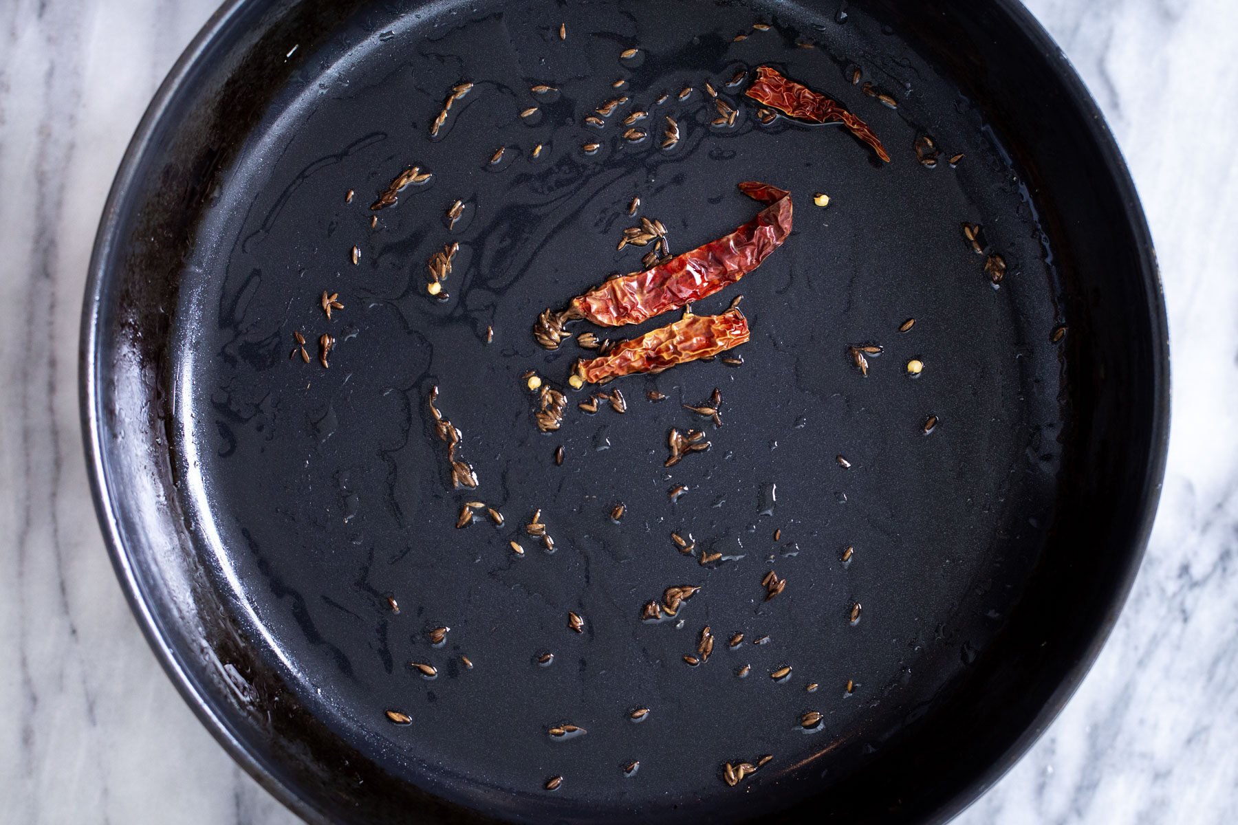 cumin seeds and chilies frying in oil to make curry
