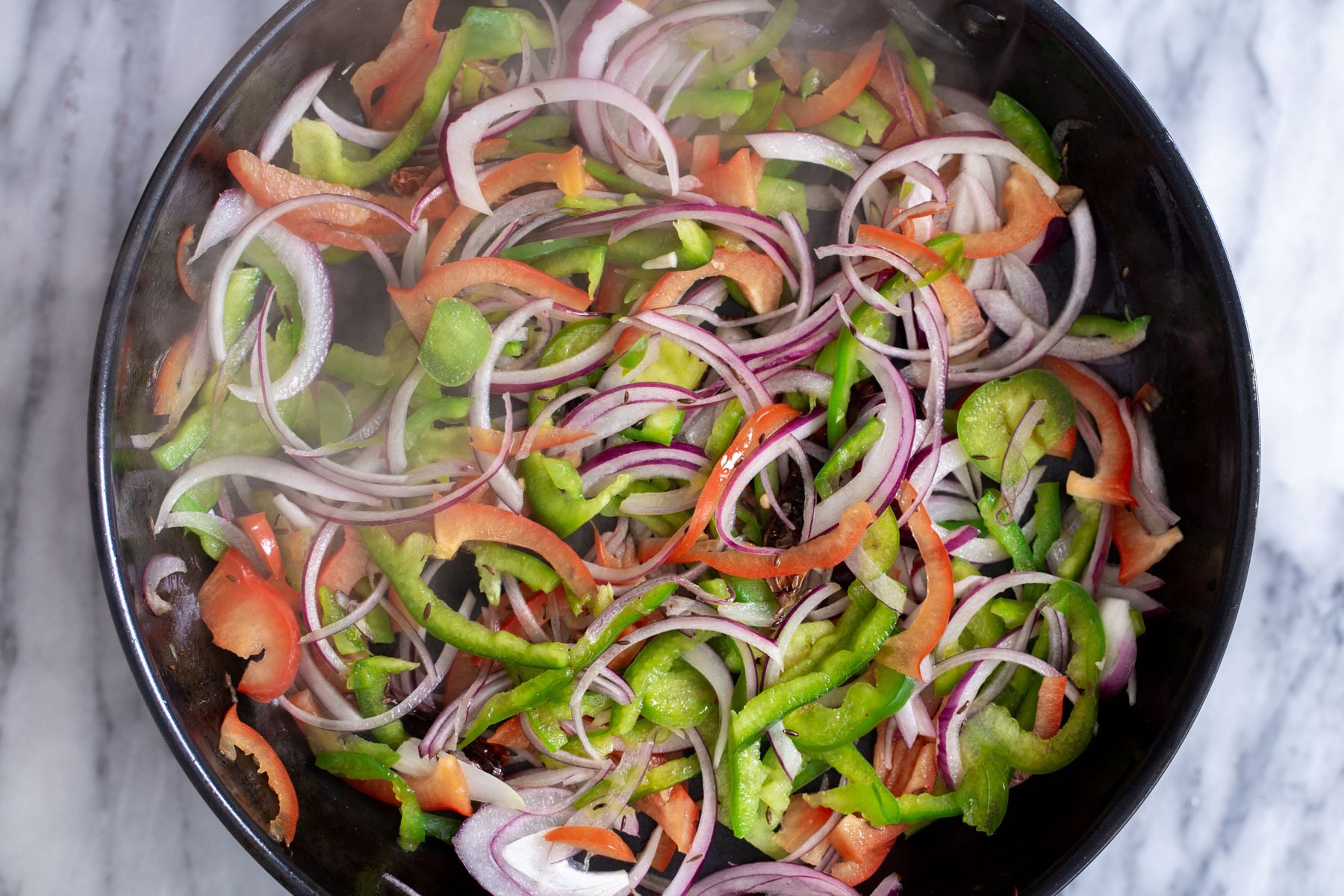 sauteed bell peppers and onions in a skillet