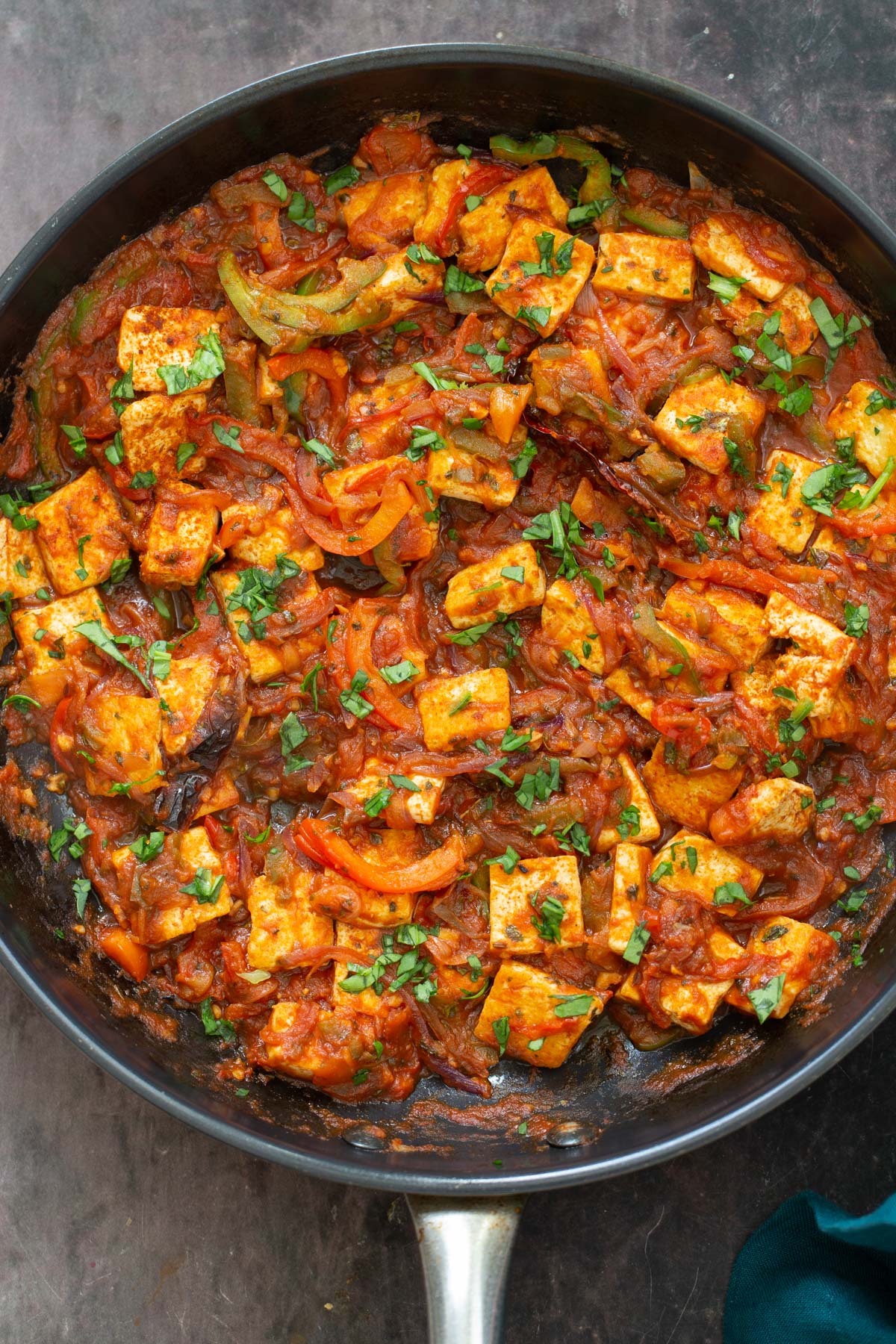 tofu jalfrezi a black skillet with tofu in jalfrezi sauce sprinkled with cilantro