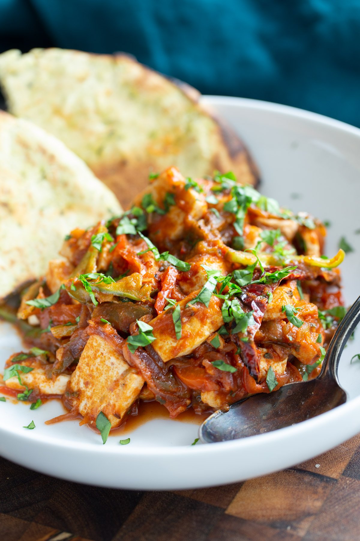 a serving of vegan jalfrezi tofu curry served with wedges of naan