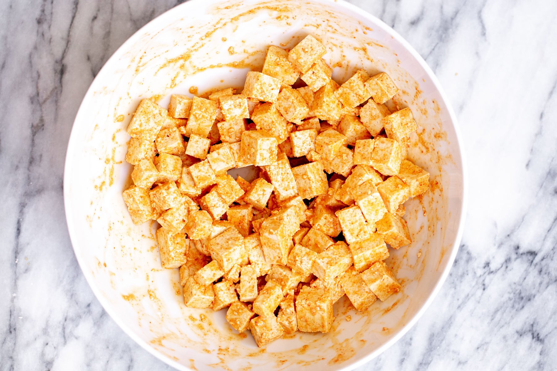 tofu cubes with spice mix in a white plate