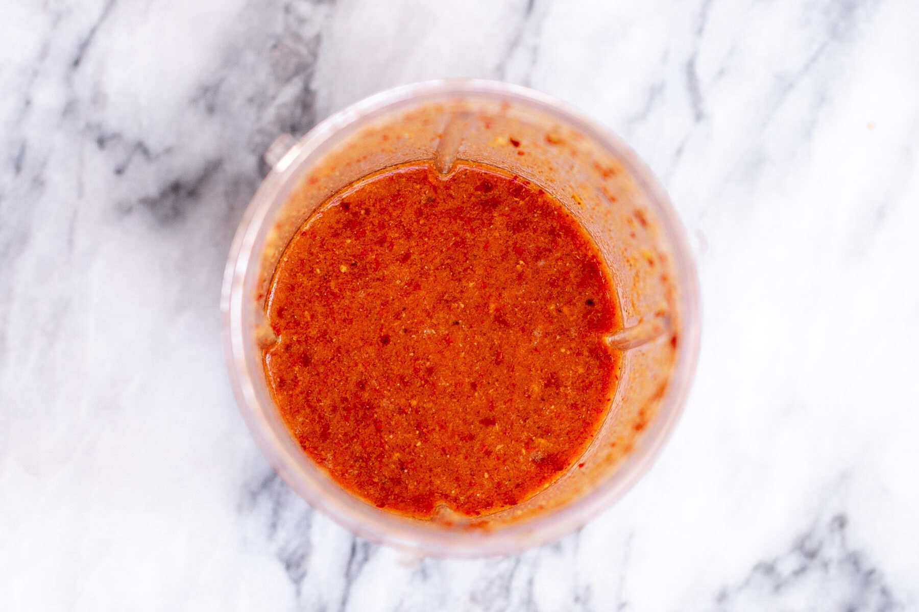 a small container with chili paste on a marble countertop