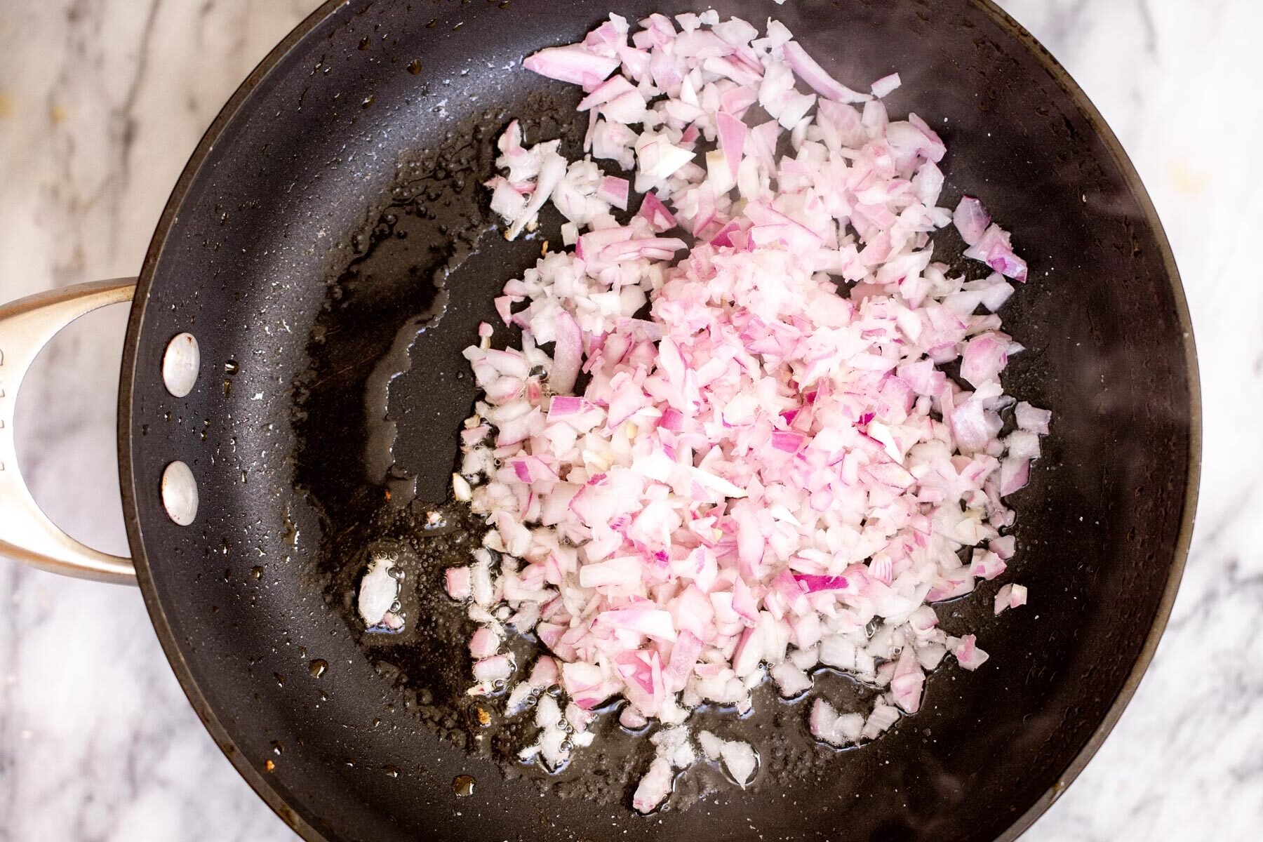chopped red onions sauteeing in black sauteeing pan