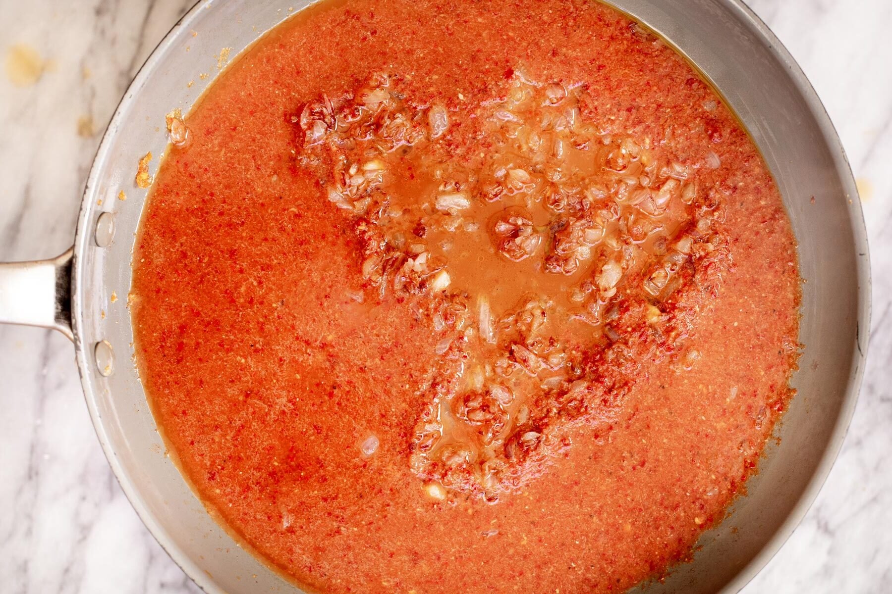 spice paste being added to a pan with fried onions