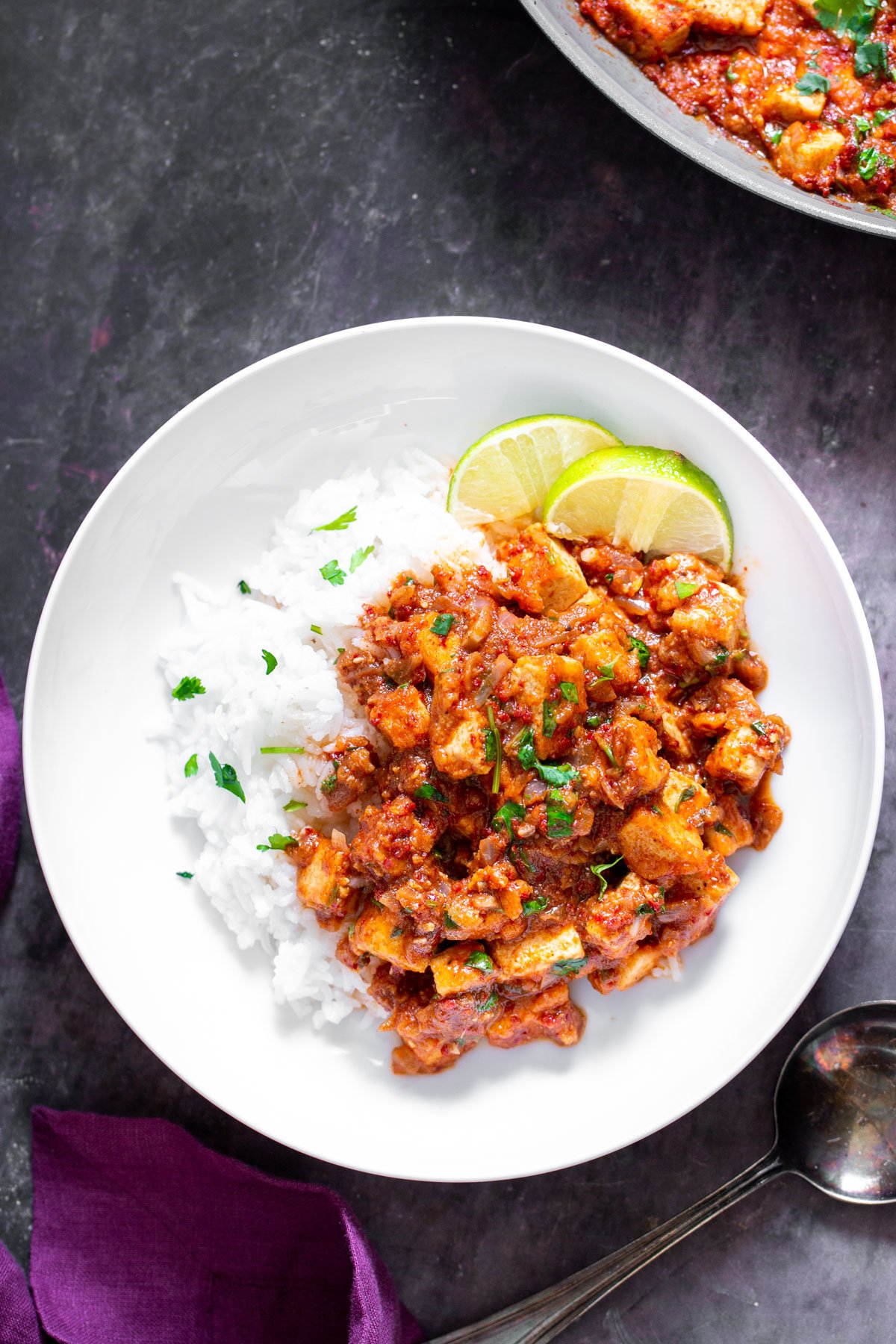 tofu vindaloo  tofu vindaloo curry served with rice on a white plate with lime slices on the side