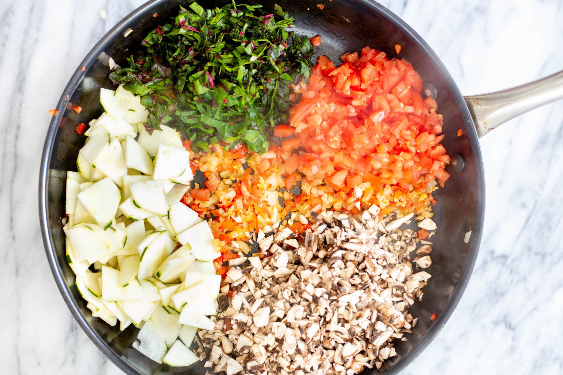 chard and chopped veggies being added to a sauteeing pan