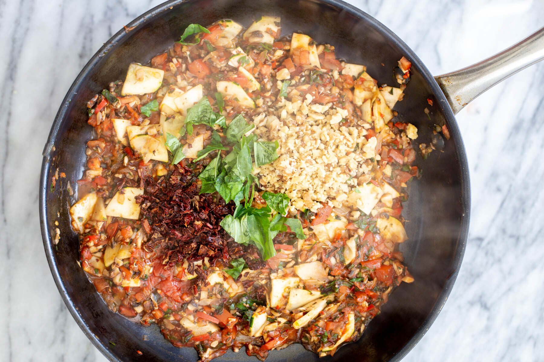 basil and sun-dried tomatoes in a sauteeing pan