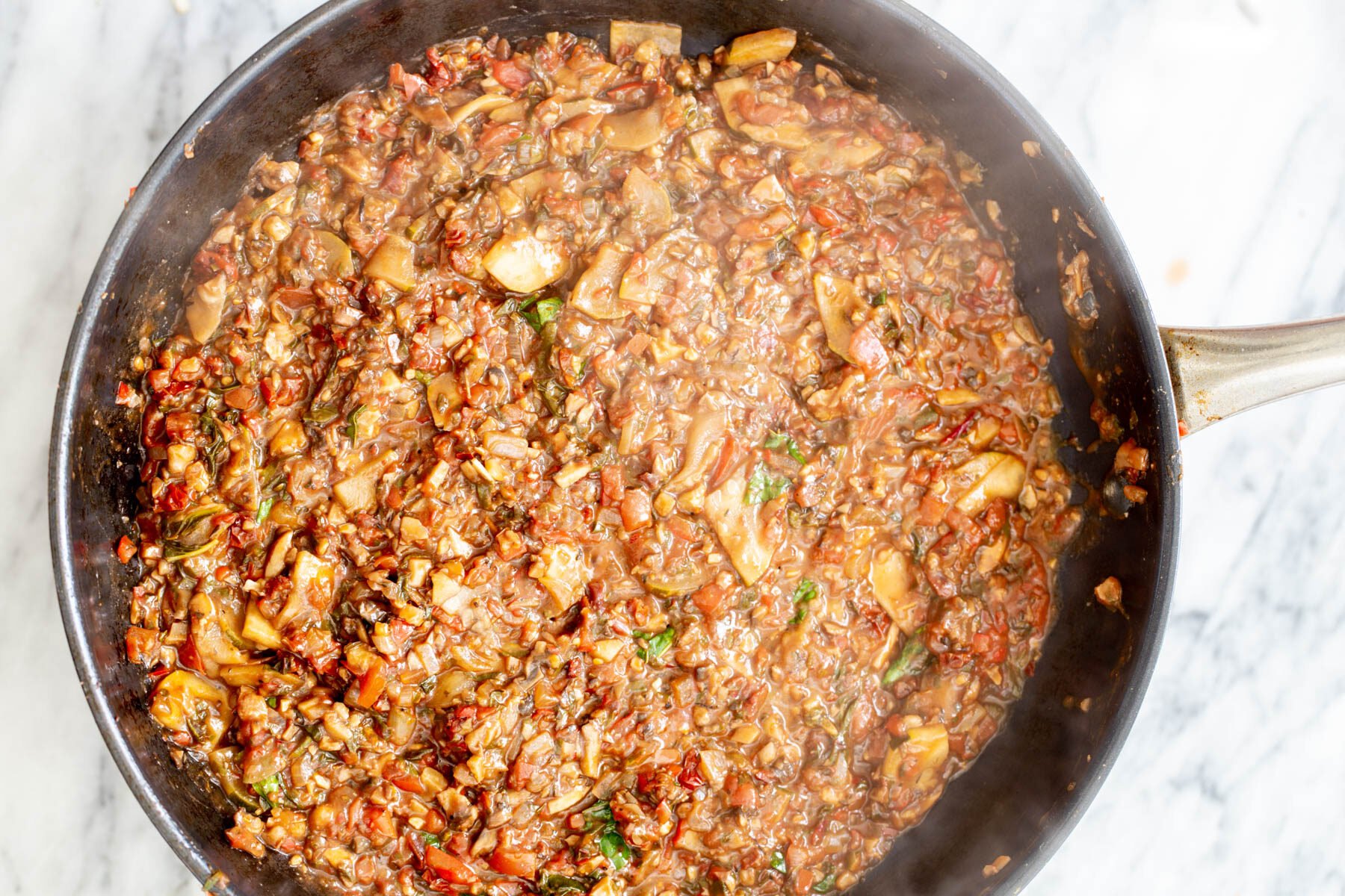 veggie ragu with chopped walnuts in a black sauteeing pan
