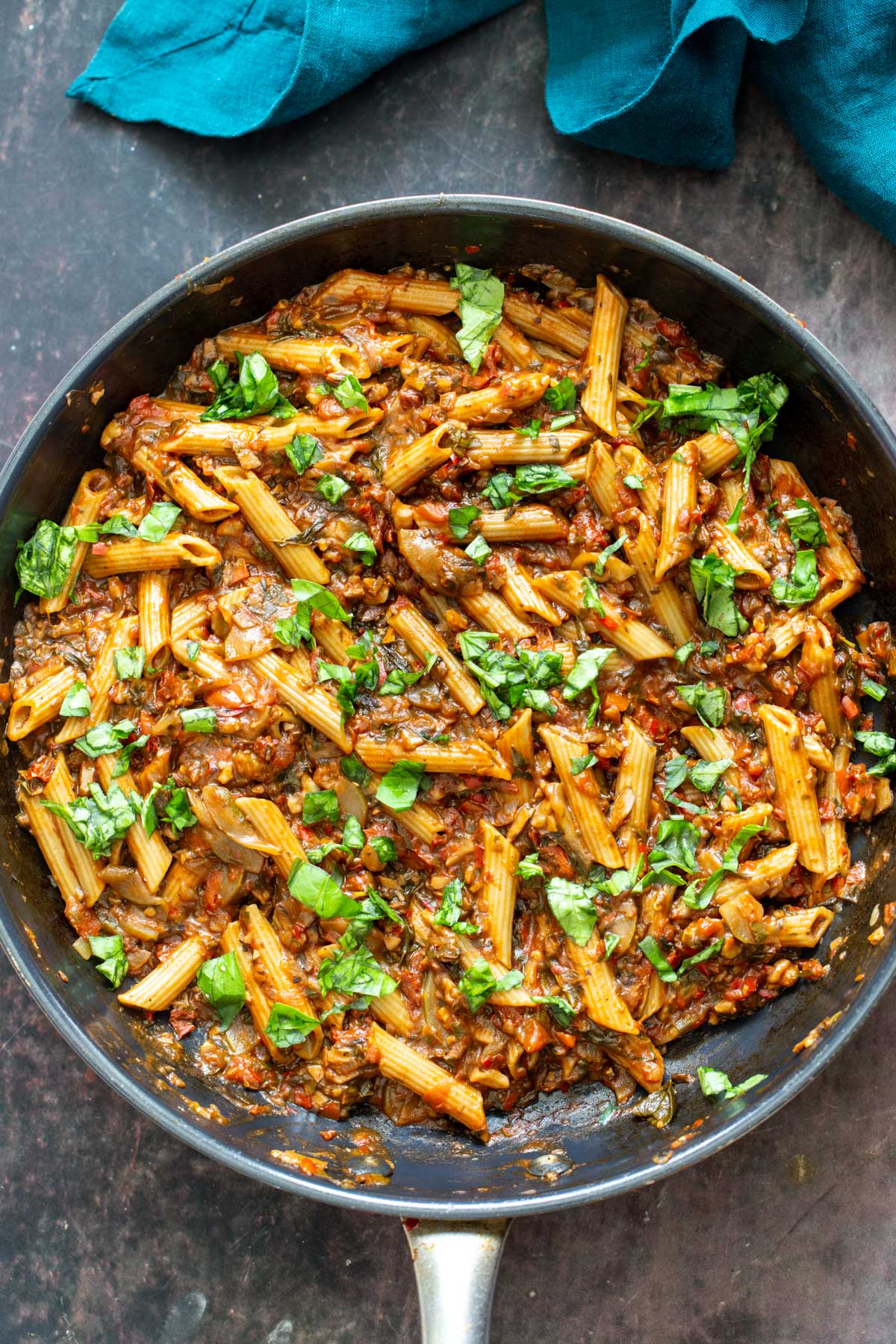 a pan with penne with walnut sun-dried tomato sauce and fresh basil
