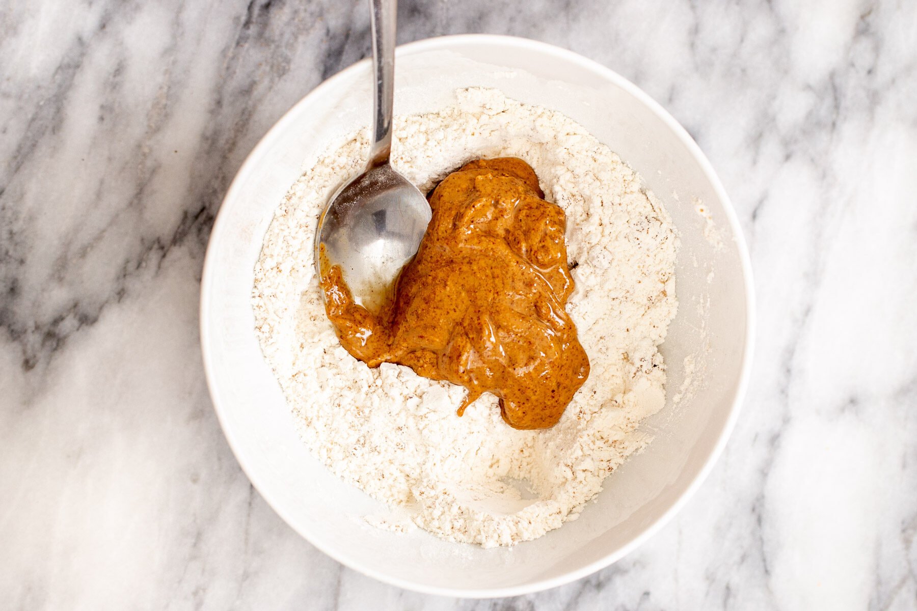 almond butter being mixed into dry crumble crust ingredients