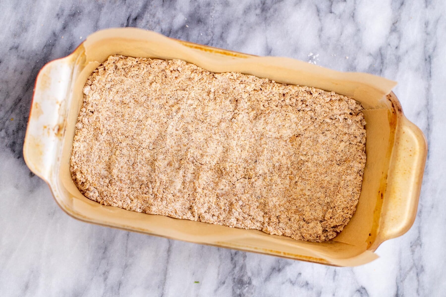 vegan apple pie crust being pressed in a baking dish