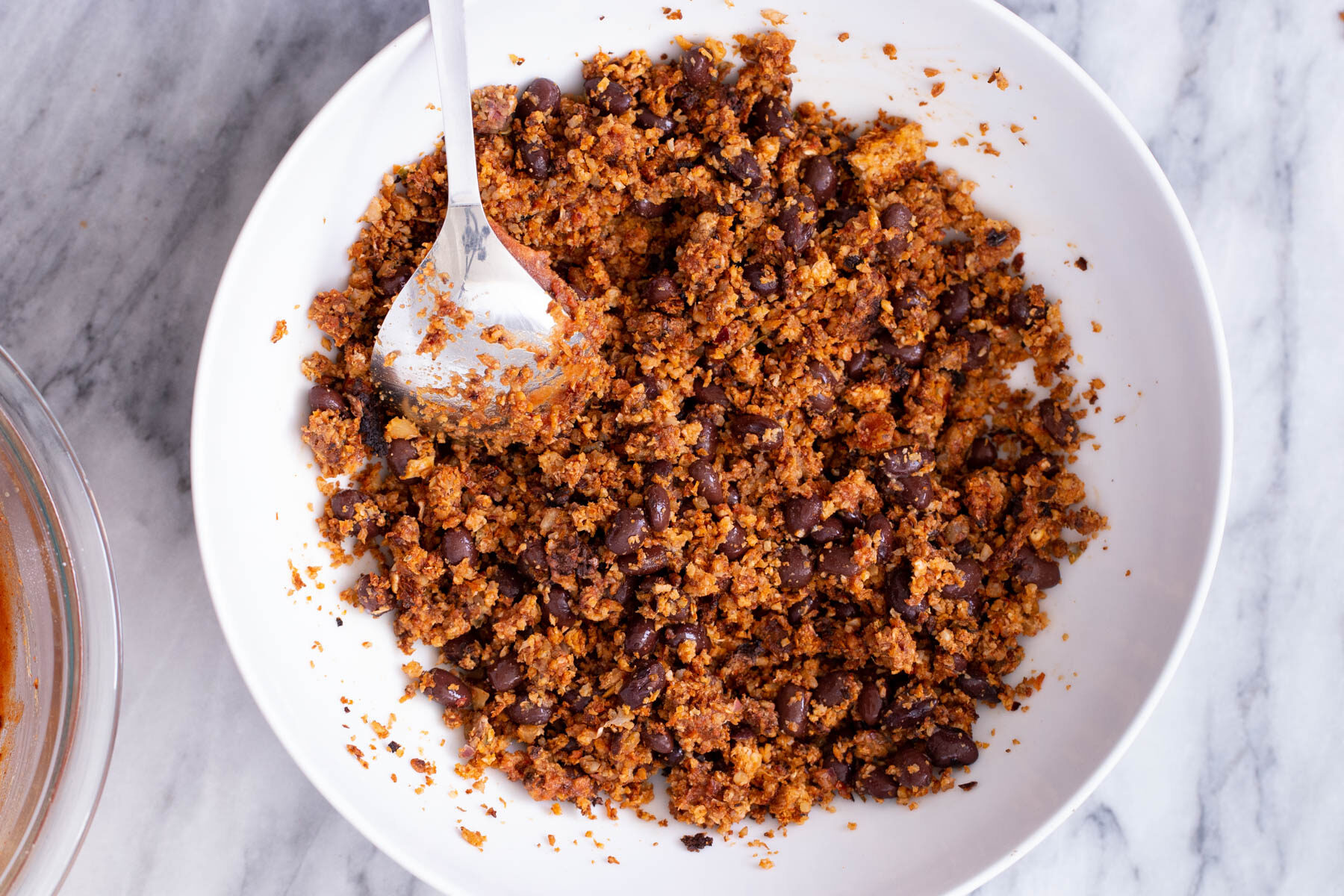 a small dish with cauliflower taco meat being mixed with kidney beans