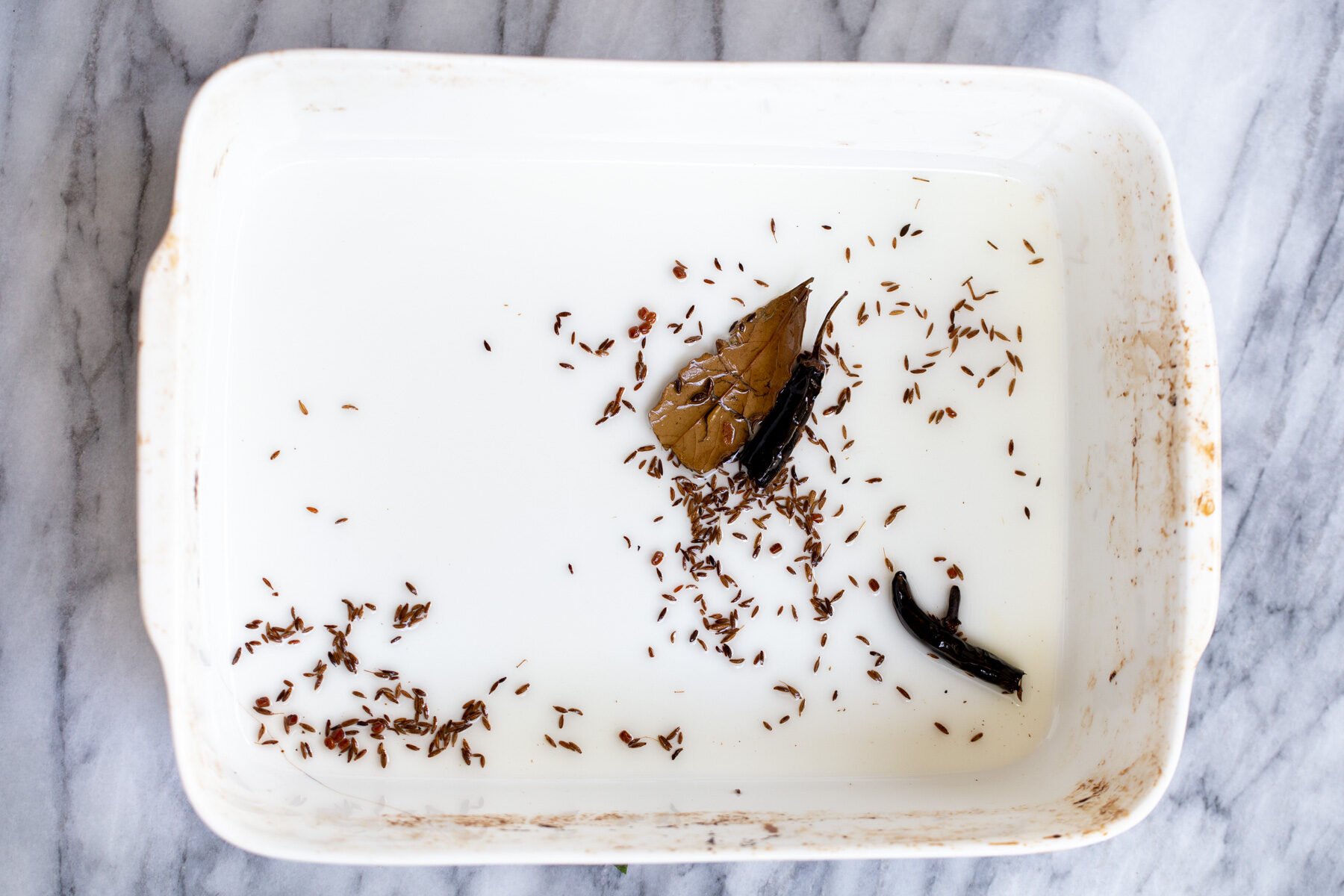 whole spices being toasted in a casserole dish