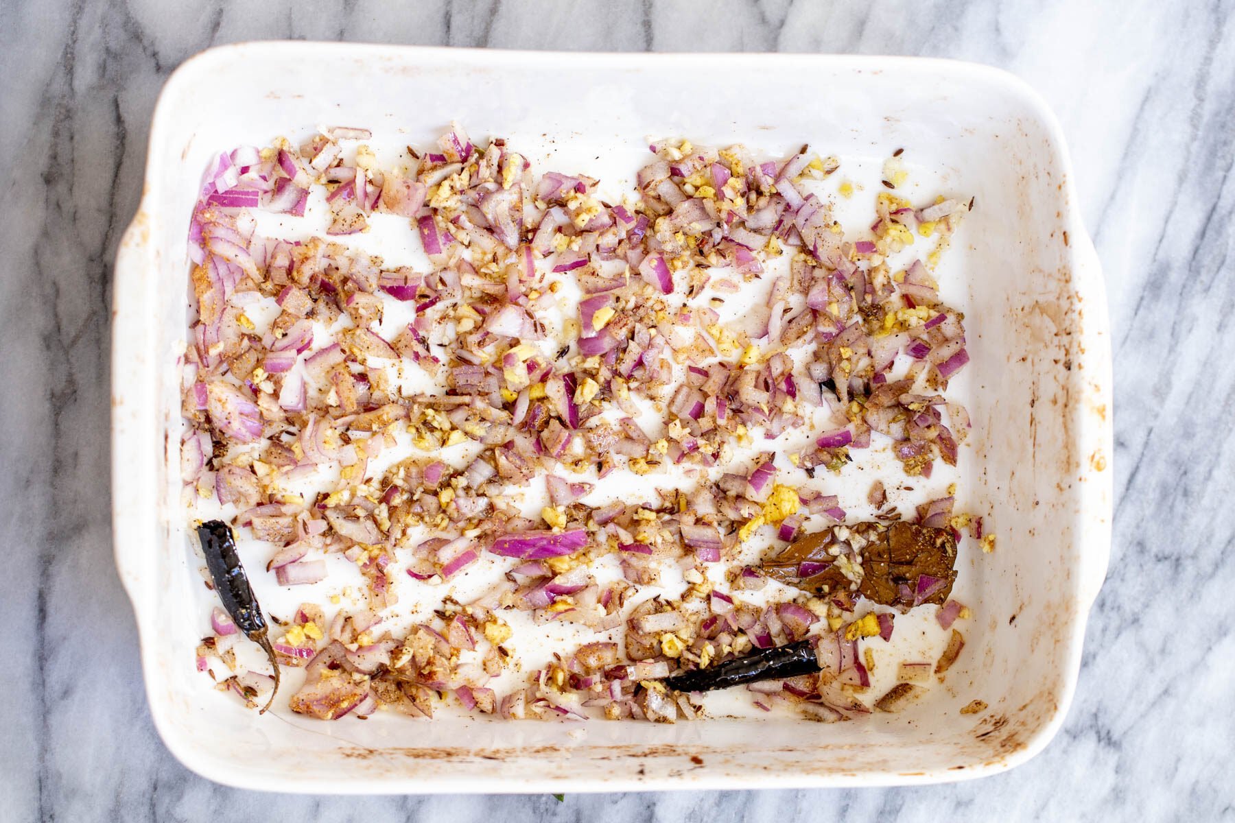 baked diced ginger and onions and spices in a white casserole dish