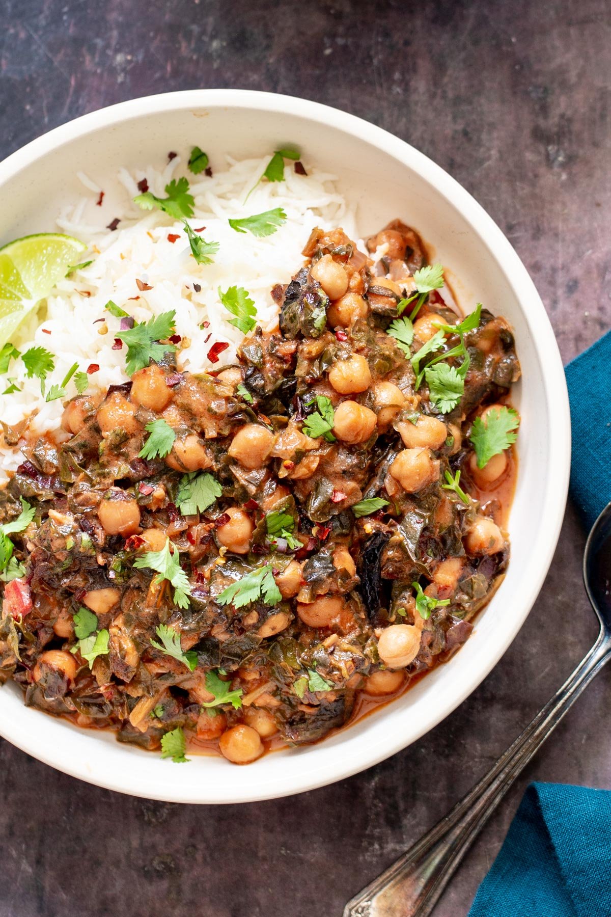 a serving of baked vegan chana saag served in a white bowl with a side of rice