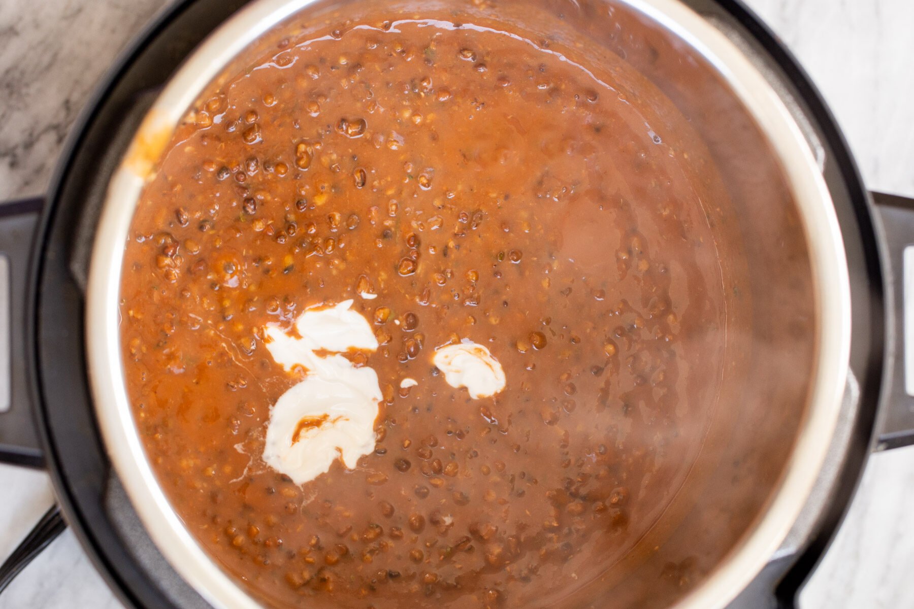 cashew cream being added to an Instant Pot of Instant Pot Bukhara