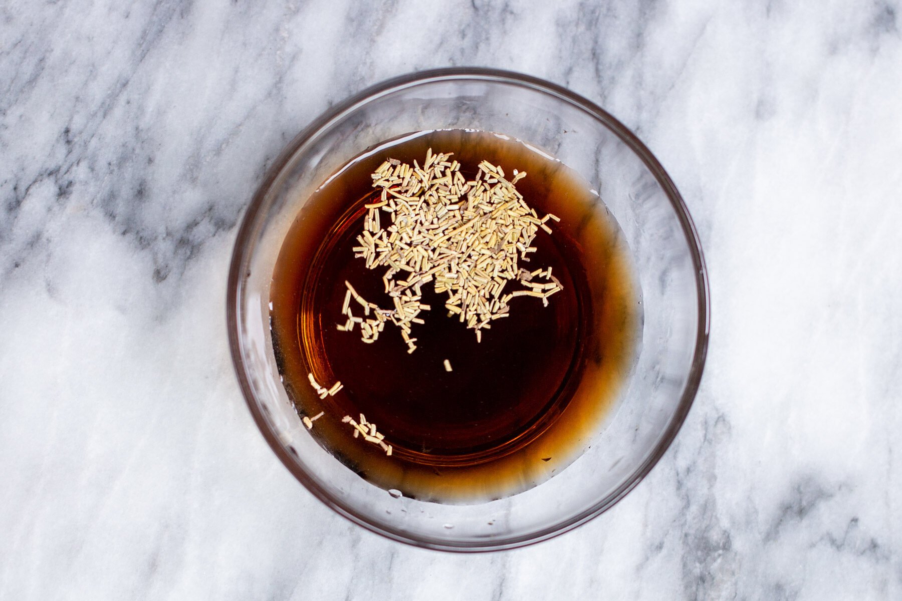 dried rosemary being mixed into balsamic vinegar