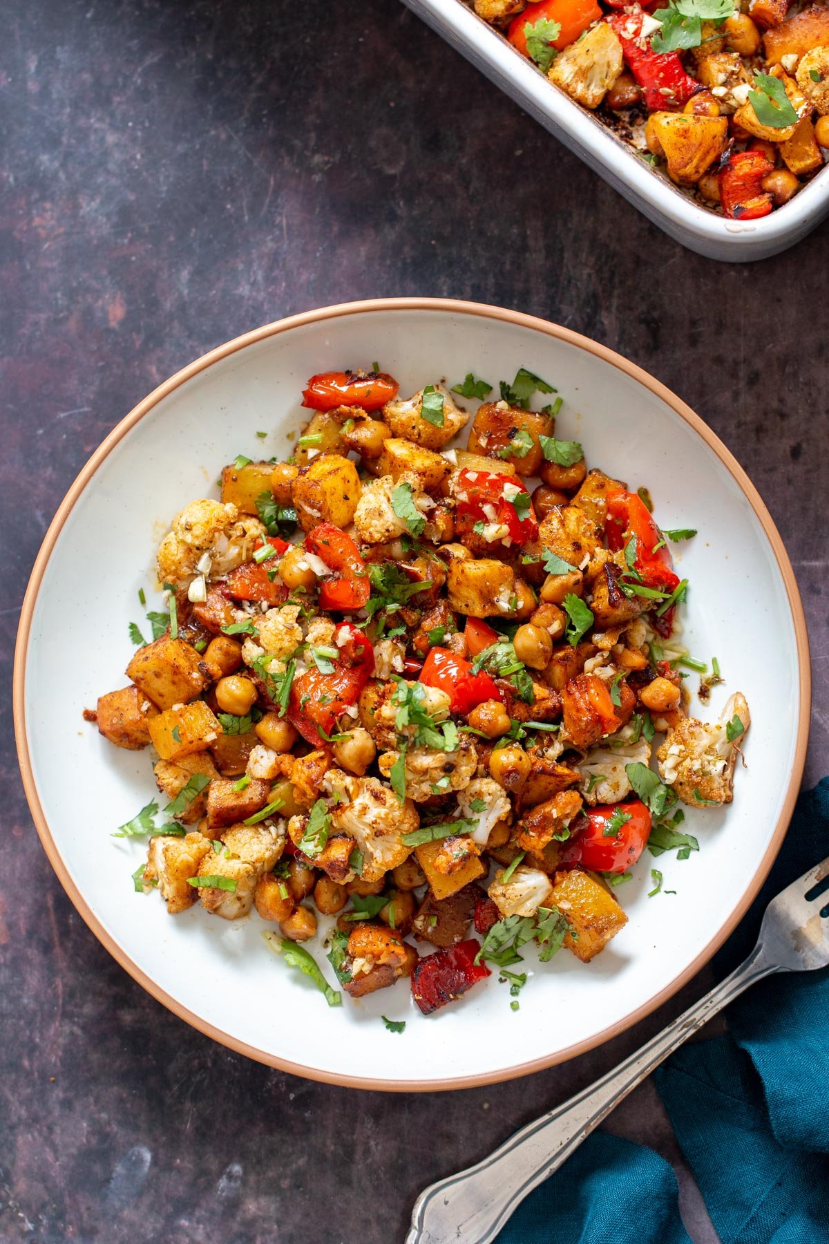 oven roasted root veggies and chickpeas served on a white plate sprinkled with cilantro