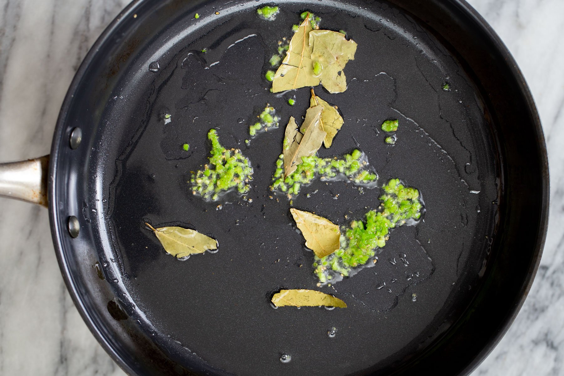 green chili and bay leaf in a sauteeing pan