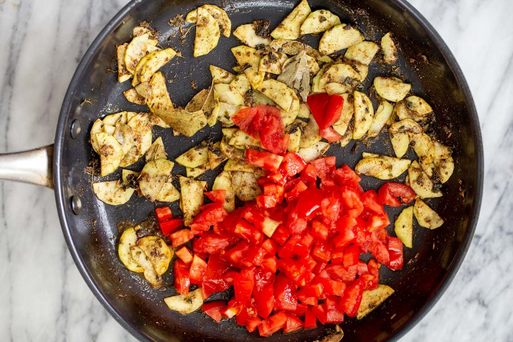 spiced zucchini and tomato chunks in a sauteeing pan