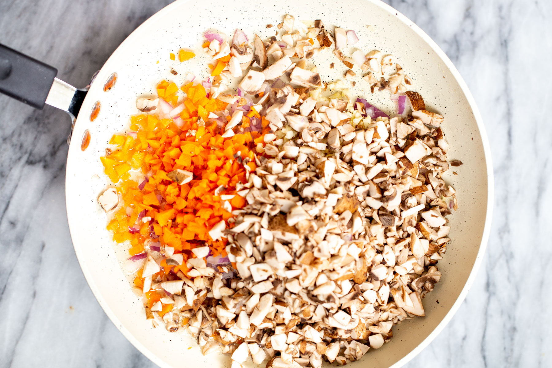chopped mushrooms and carrots in a sauteeing pan