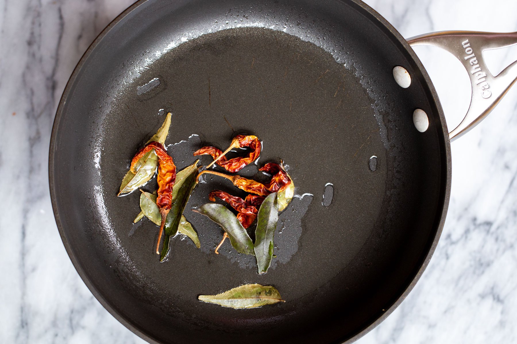 chilies and curry leaves in a black skillet