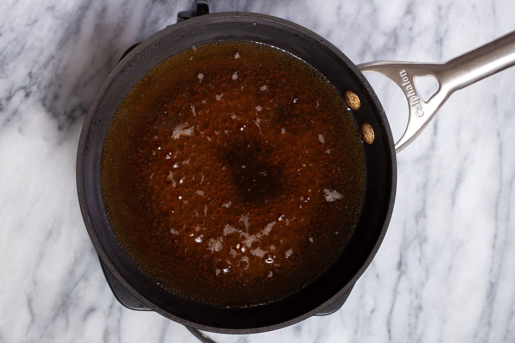 baklava soaking syurp in a black saucepan