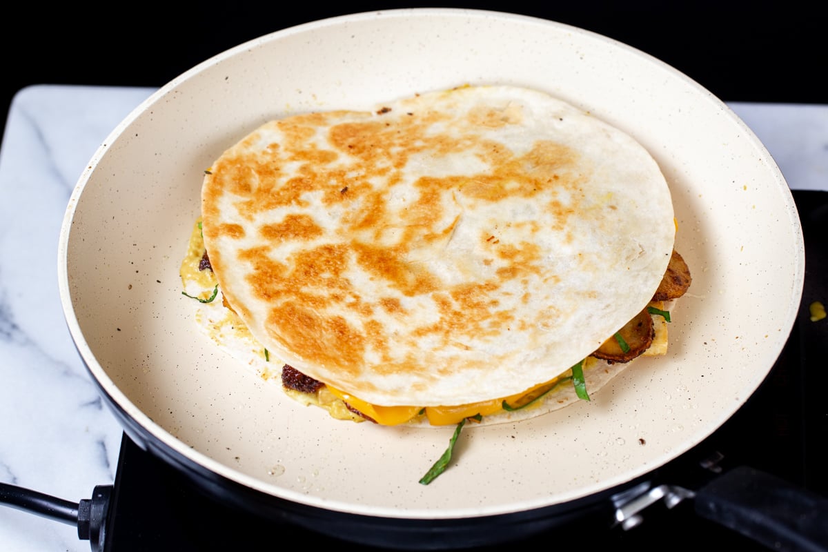 quesadilla being browned in a pan