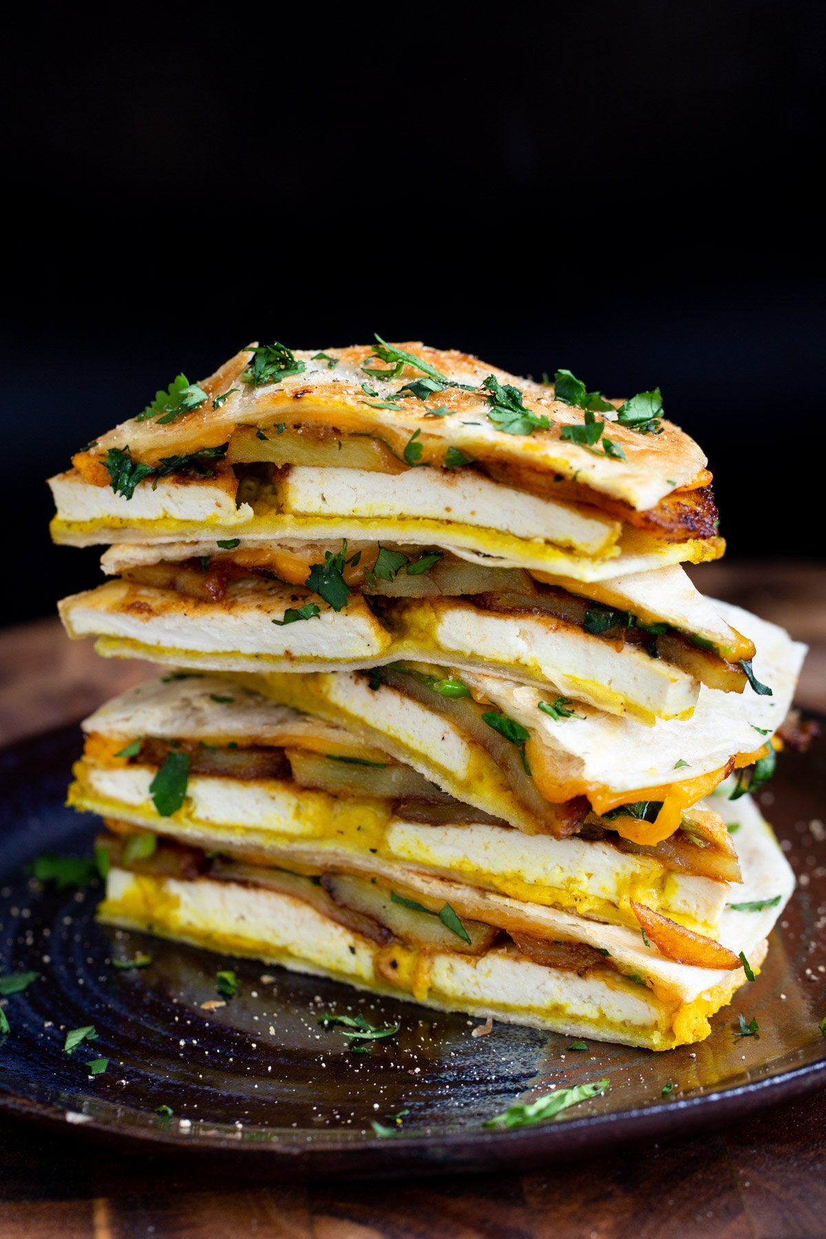 stacked vegan breakfast quesadilla with hummus, tofu and potatoes