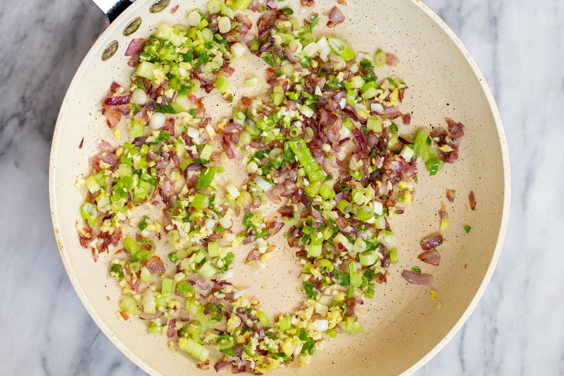 chopped green onion, garlic and ginger in a frying pan