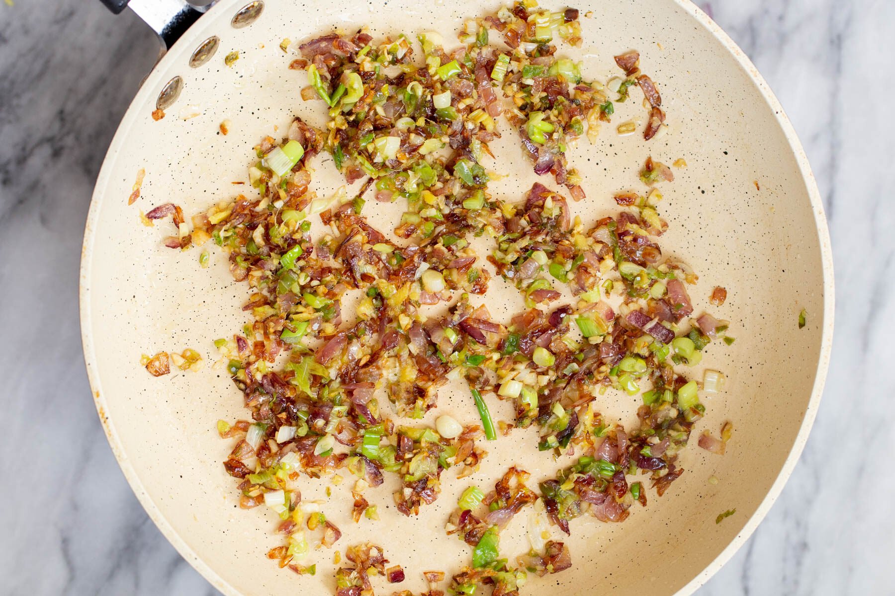 garlic, green chili and onion in a frying pan